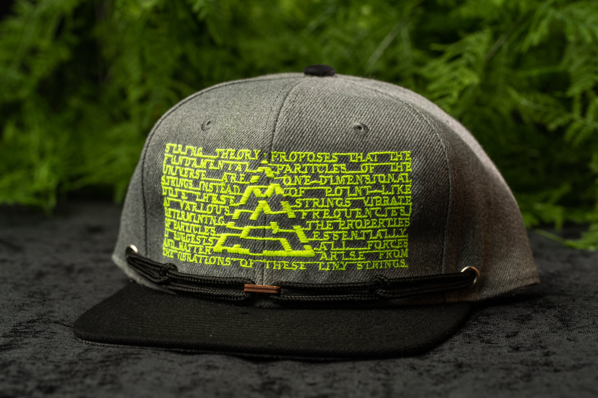 A gray baseball cap with a unique graphic design on the front, featuring a pattern of yellow and green text and shapes.