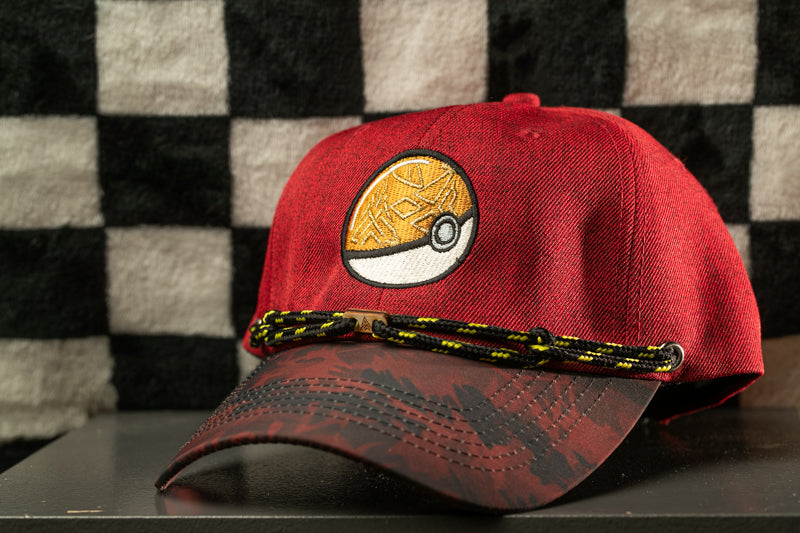 A red baseball cap with a Pokemon-themed design is displayed against a black and white checkered background.