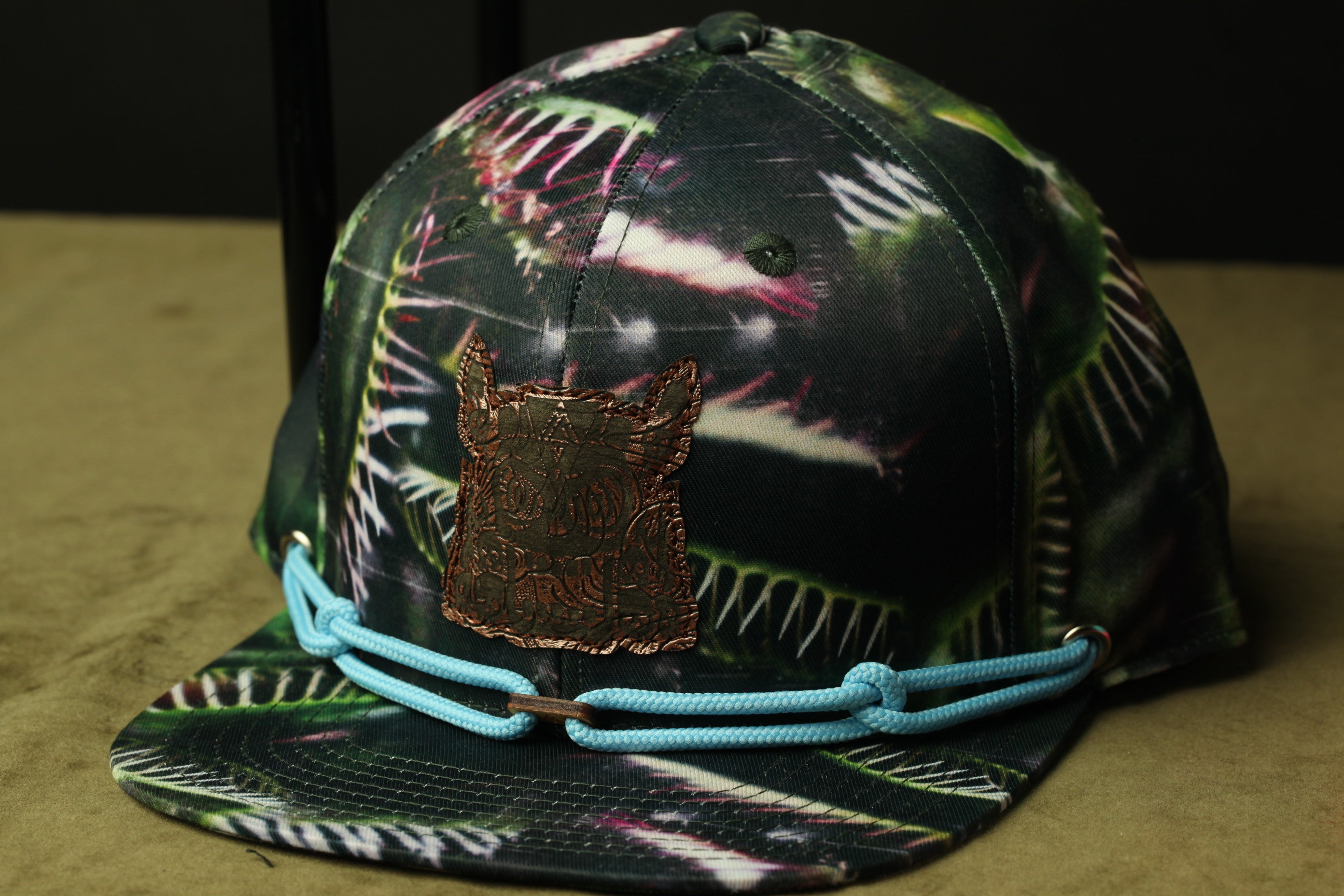 A colorful, patterned baseball cap with a metal patch on the front.
