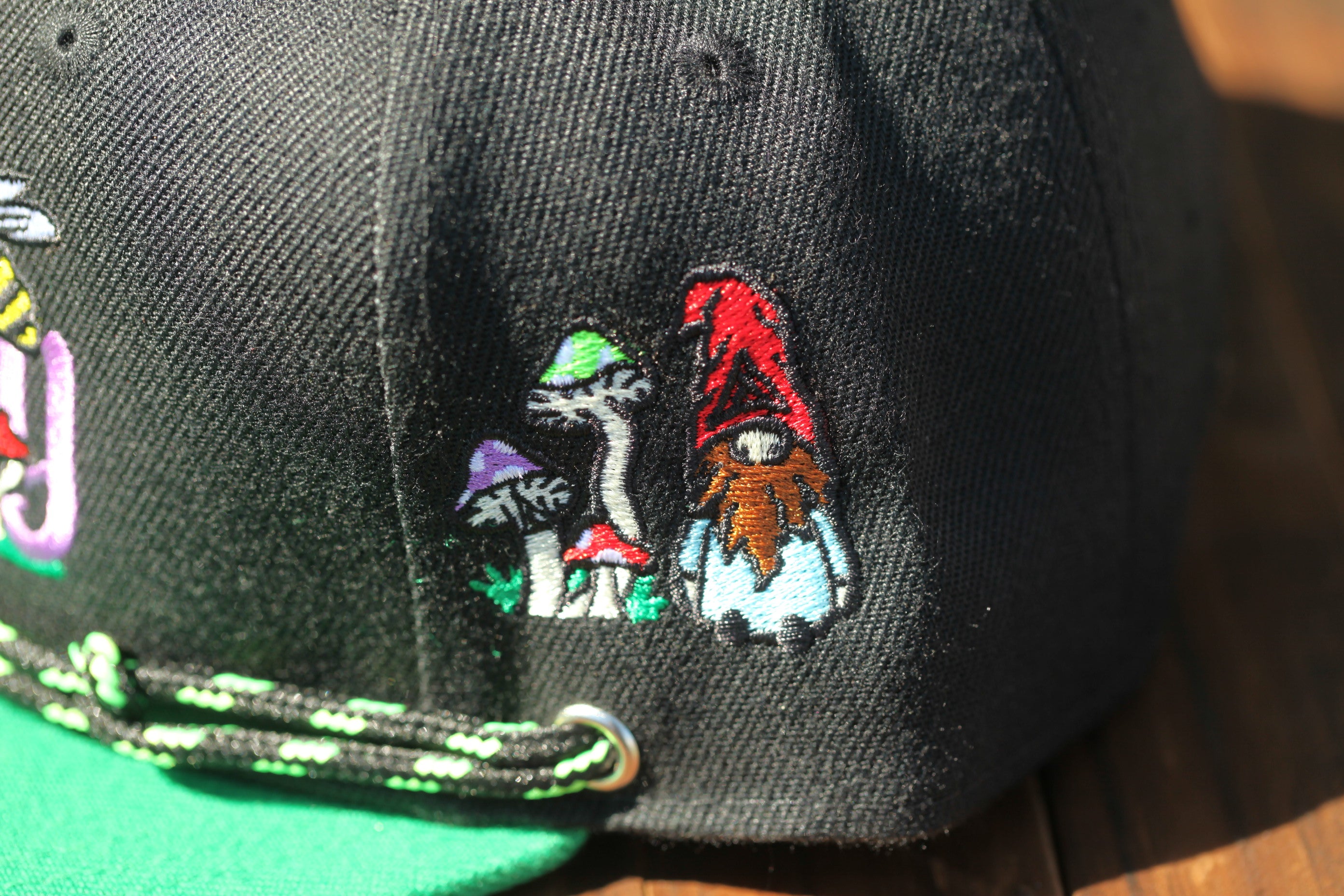 a close-up view of a black baseball cap with colorful embroidered designs on the front.