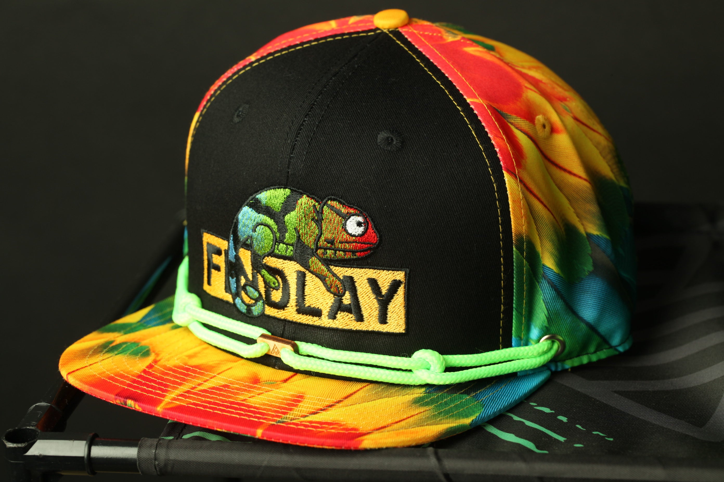 A colorful tie-dye baseball cap with a chameleon design and the word "FOOLAY" printed on it.