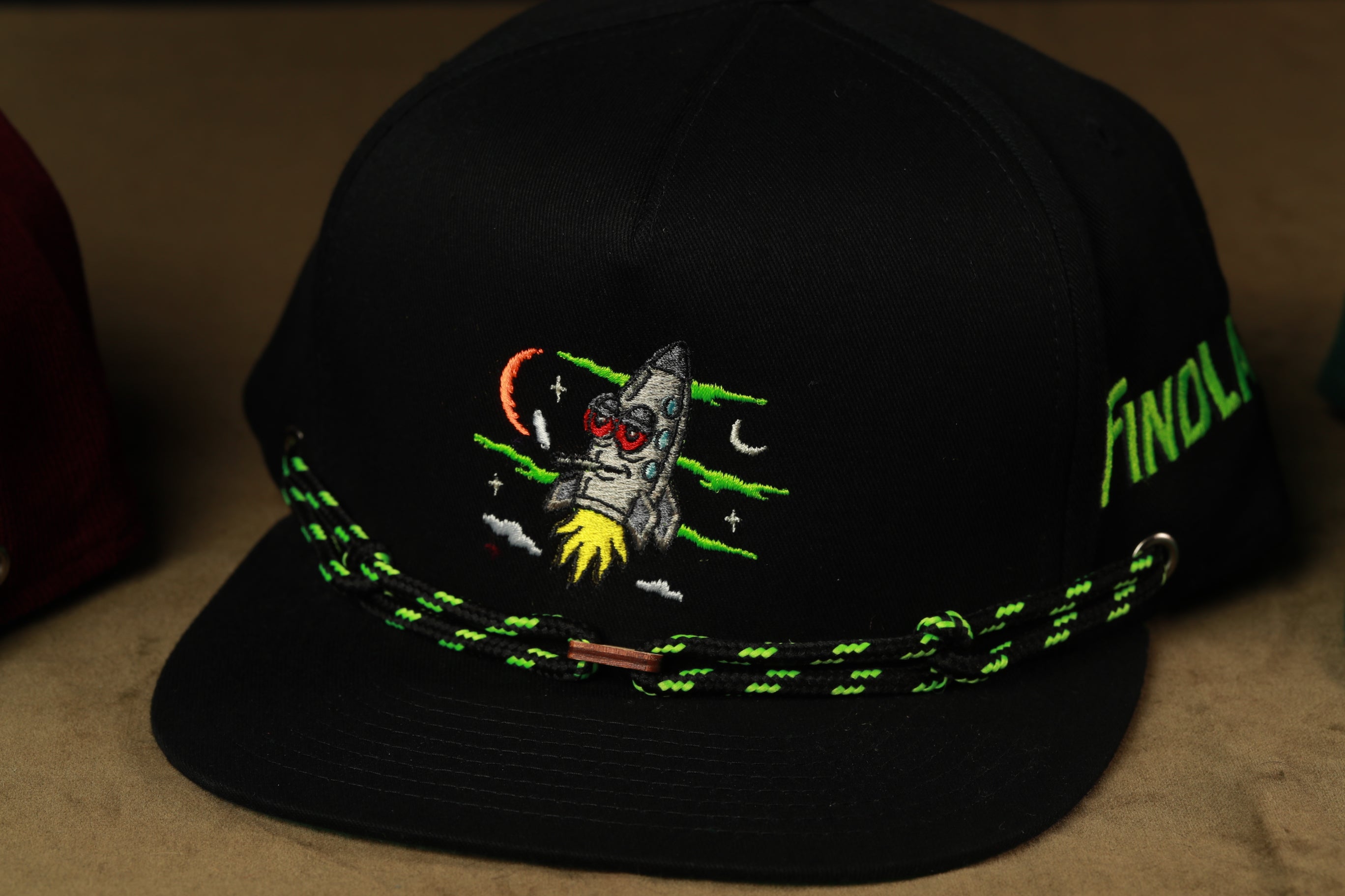 A black baseball cap with a colorful, space-themed embroidered design on the front.