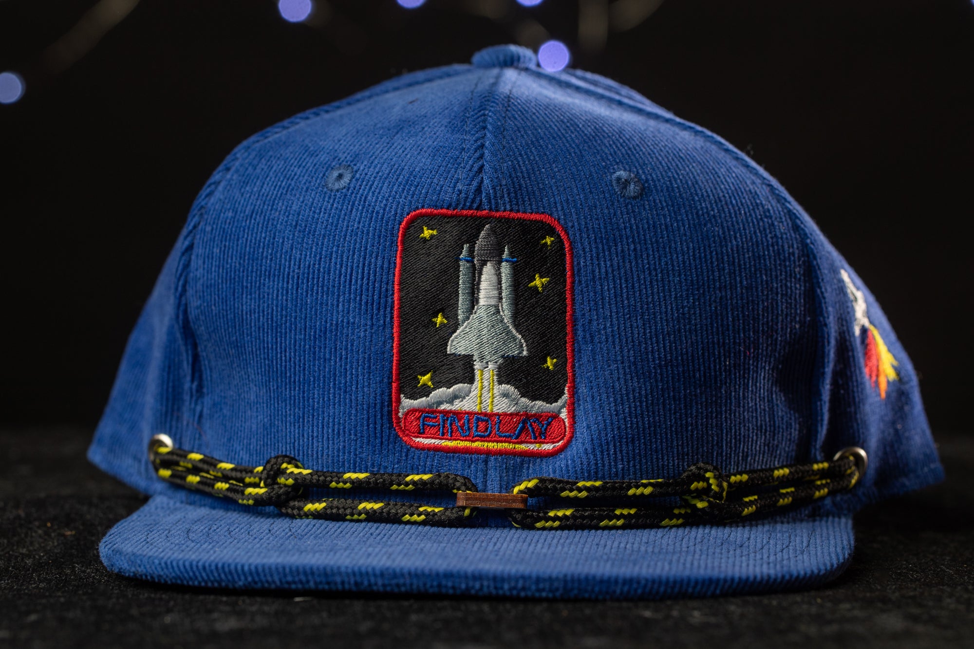 A blue baseball cap with a red and white patch on the front, featuring a rocket ship and the word "ENDO" printed on it.