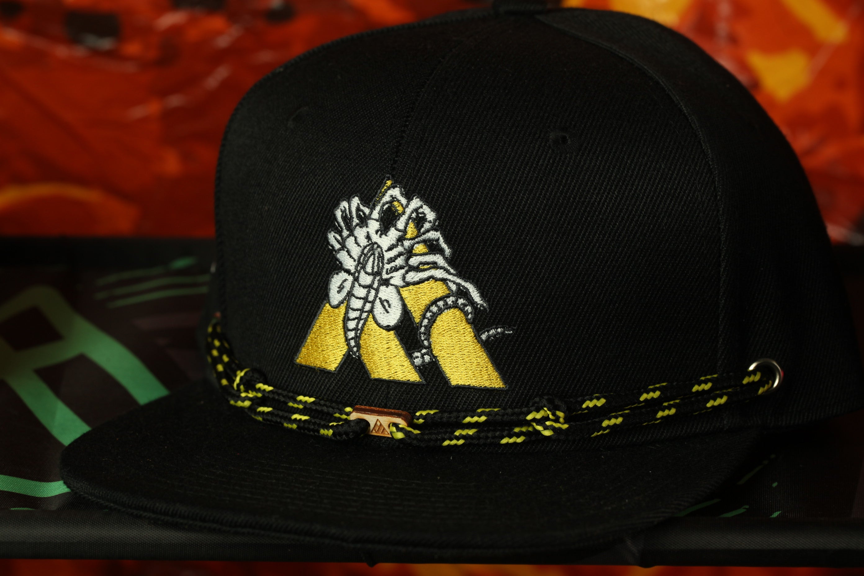 A black baseball cap with a yellow and white embroidered logo on the front.