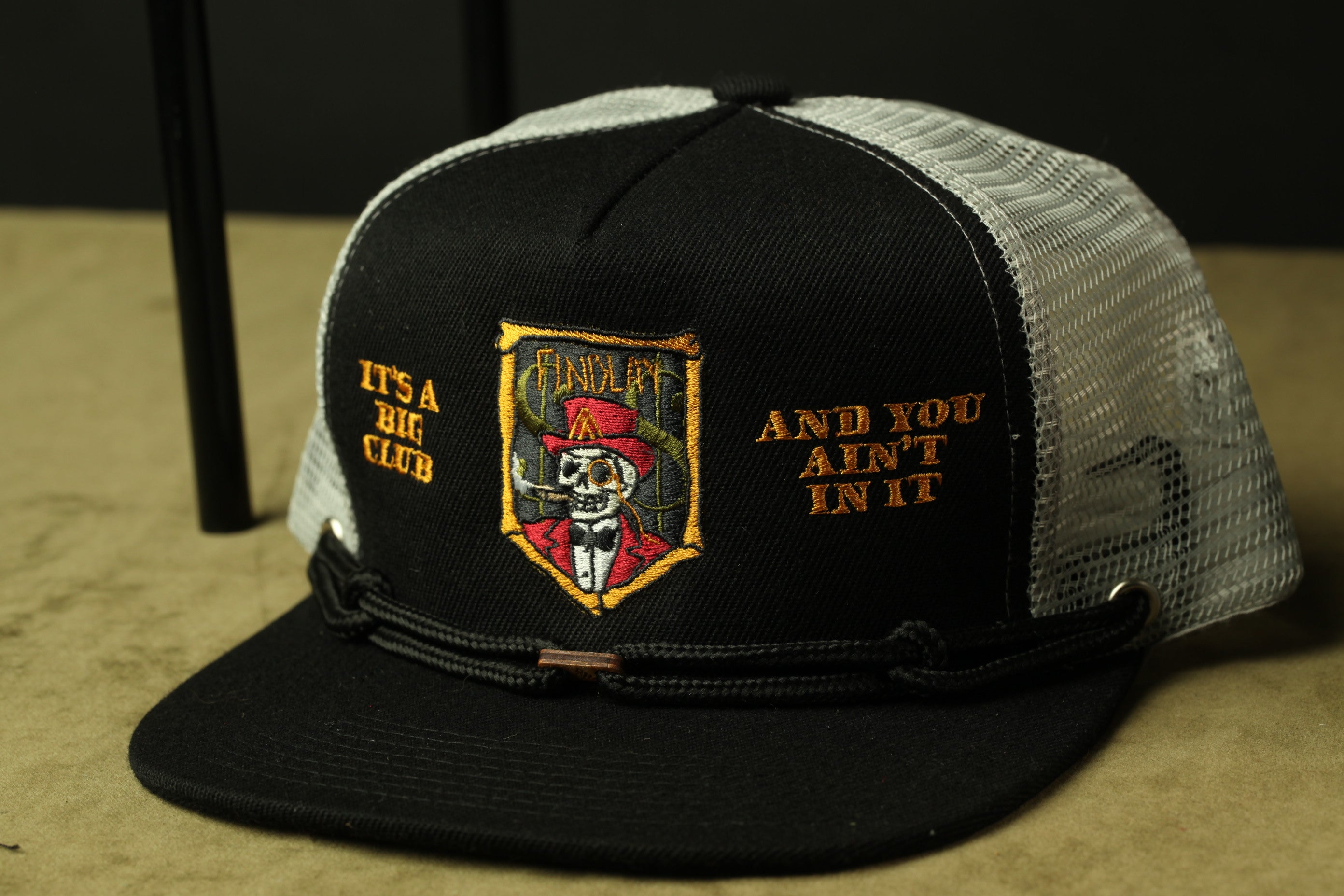 A black baseball cap with a mesh panel and a patch featuring a skull and crossbones design.