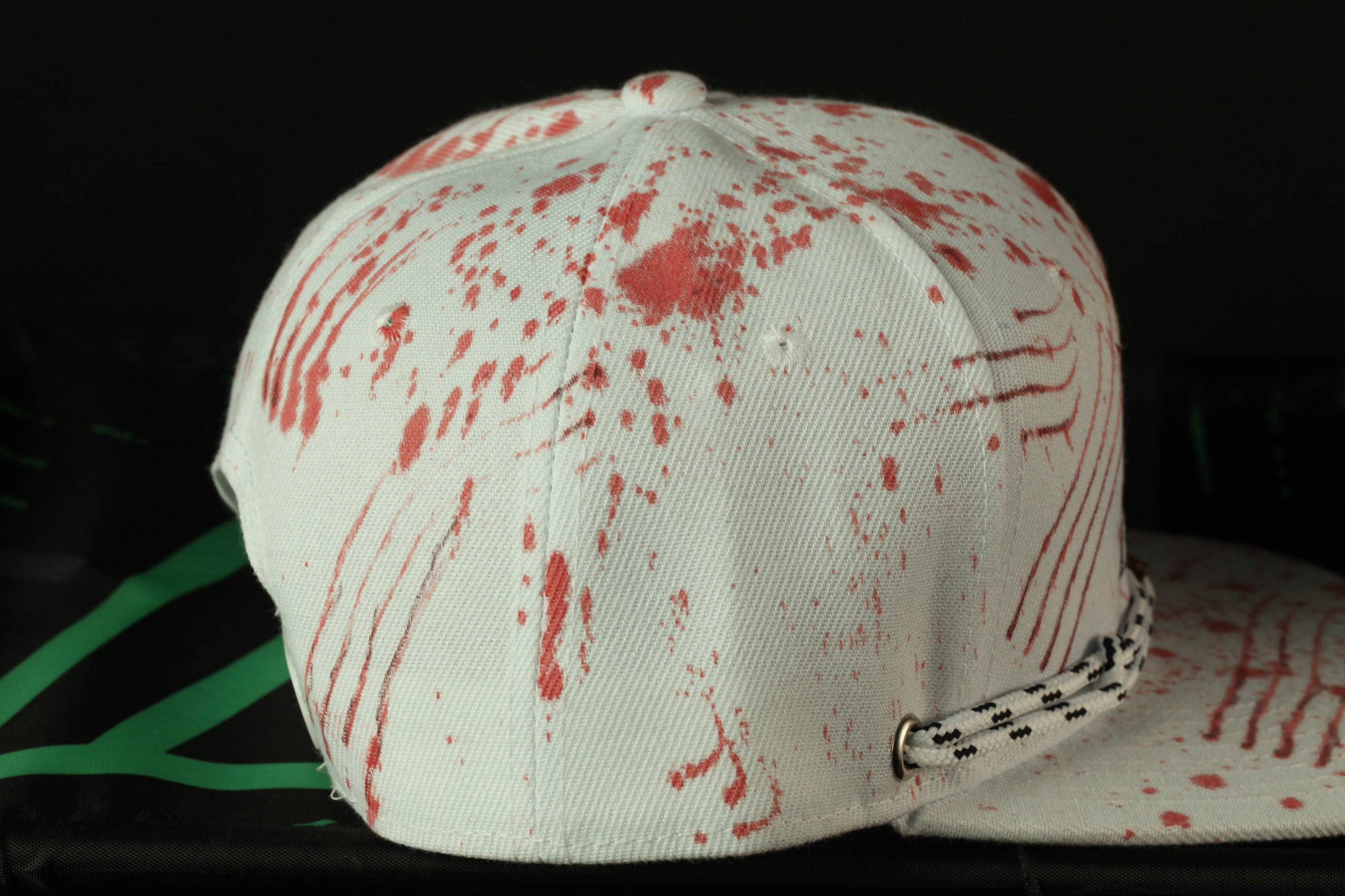 A white baseball cap with red splatters is shown in the image.
