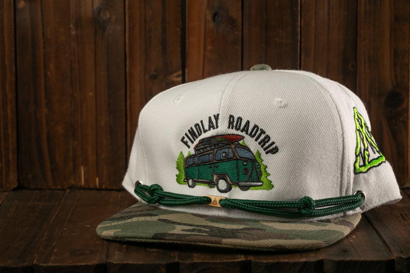 A white baseball cap with a green and camouflage pattern, featuring an embroidered image of a van and the text "Findlay Roadtrip" on the front.