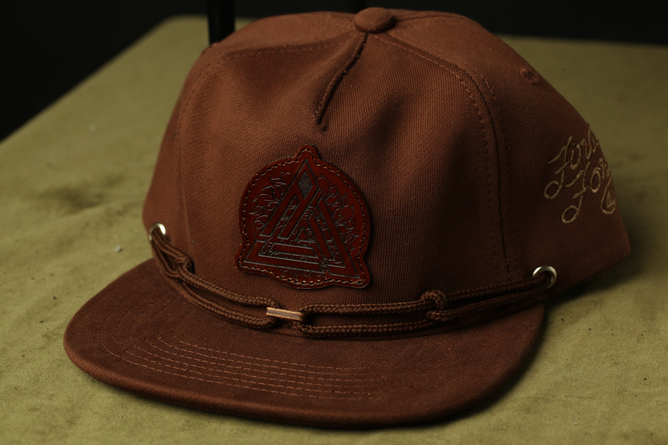 A brown baseball cap with a leather patch and metal buckle.