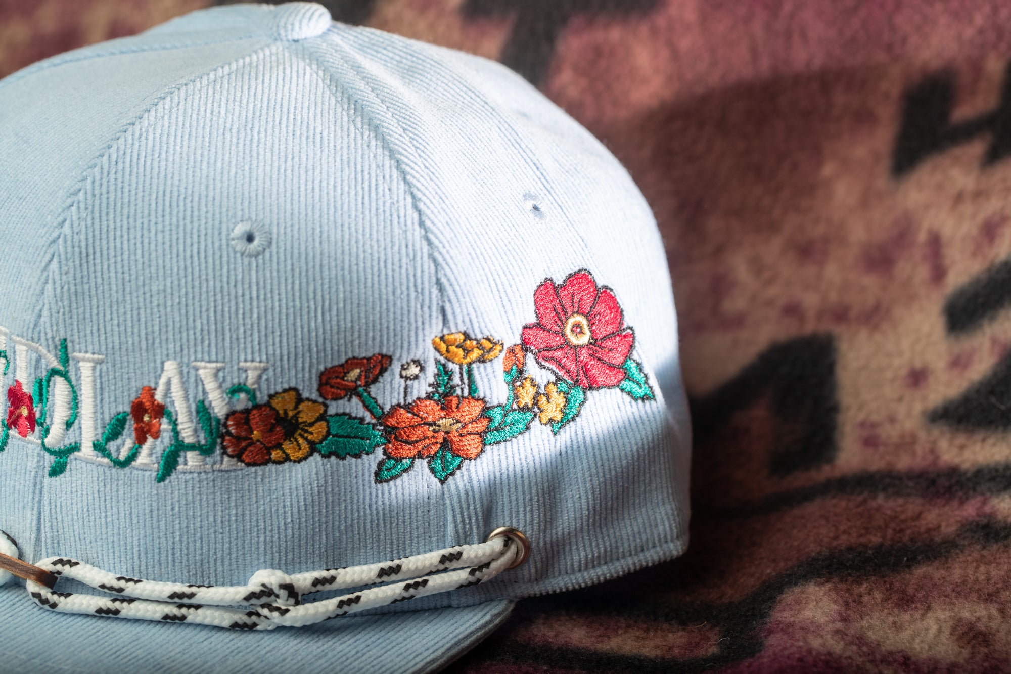 A light blue baseball cap with colorful floral embroidery on the front.