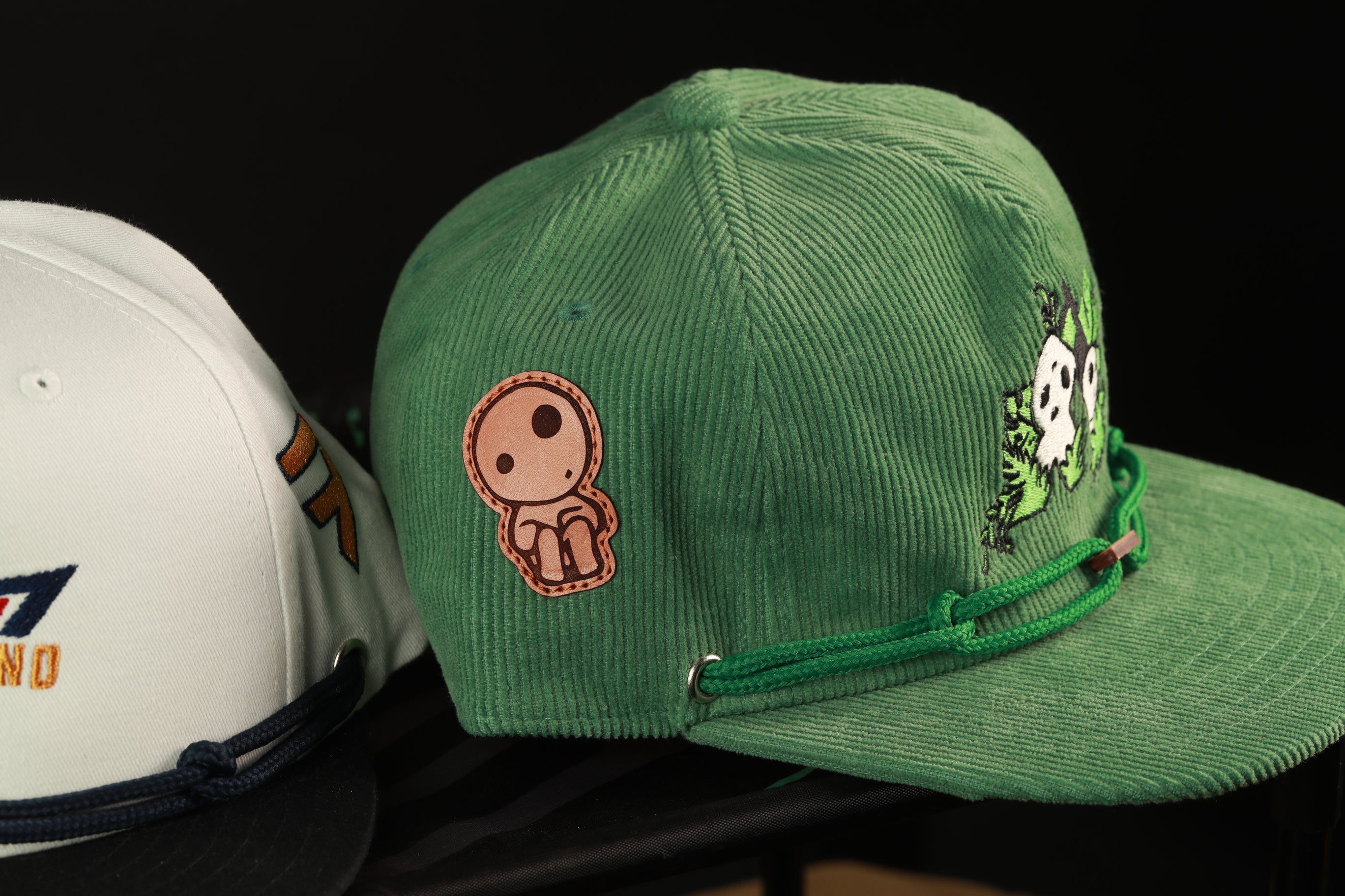 two baseball caps, one green and one white, placed side by side.