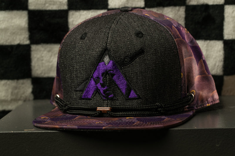 A black baseball cap with a purple and purple floral pattern, featuring a purple logo on the front.