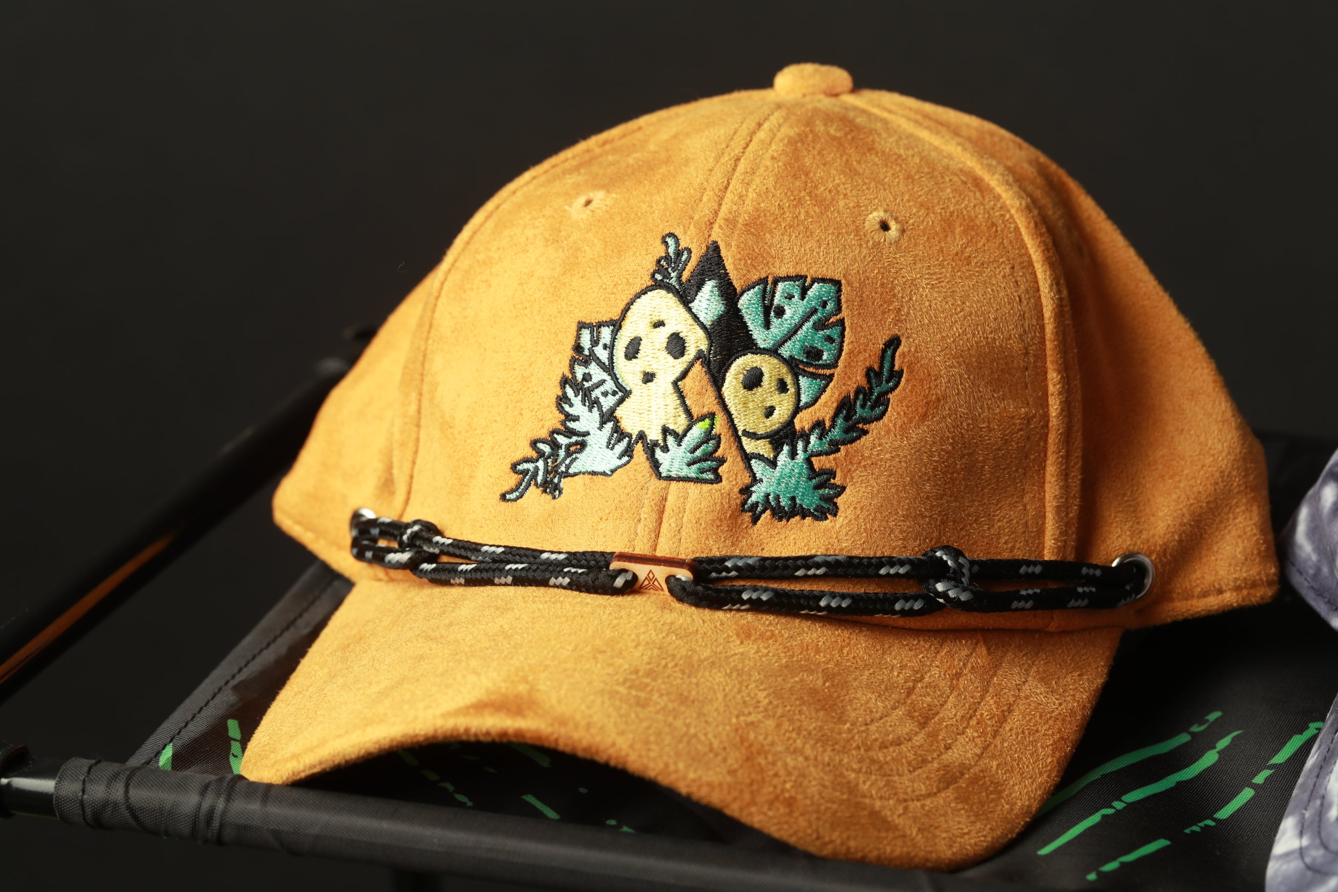 A yellow baseball cap with a cartoon character design on it, sitting on a black surface.