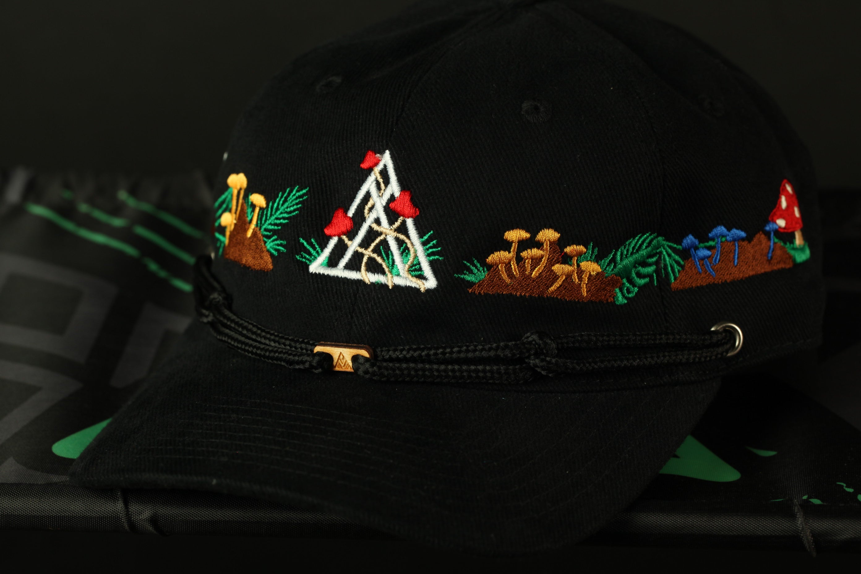 A black baseball cap with colorful floral and geometric embroidery designs on the brim.
