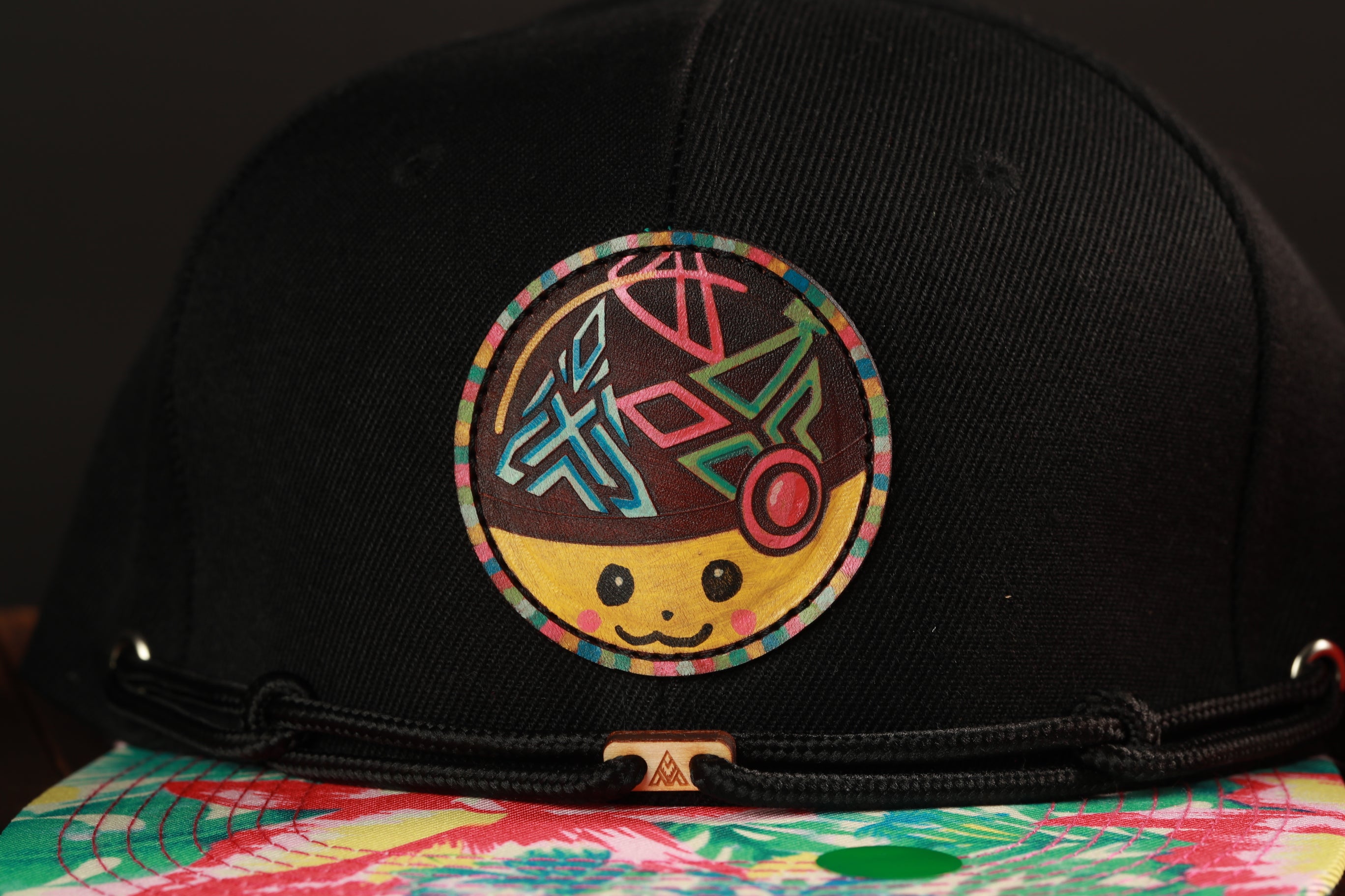 A close-up view of a black baseball cap with a colorful, abstract design on the front.