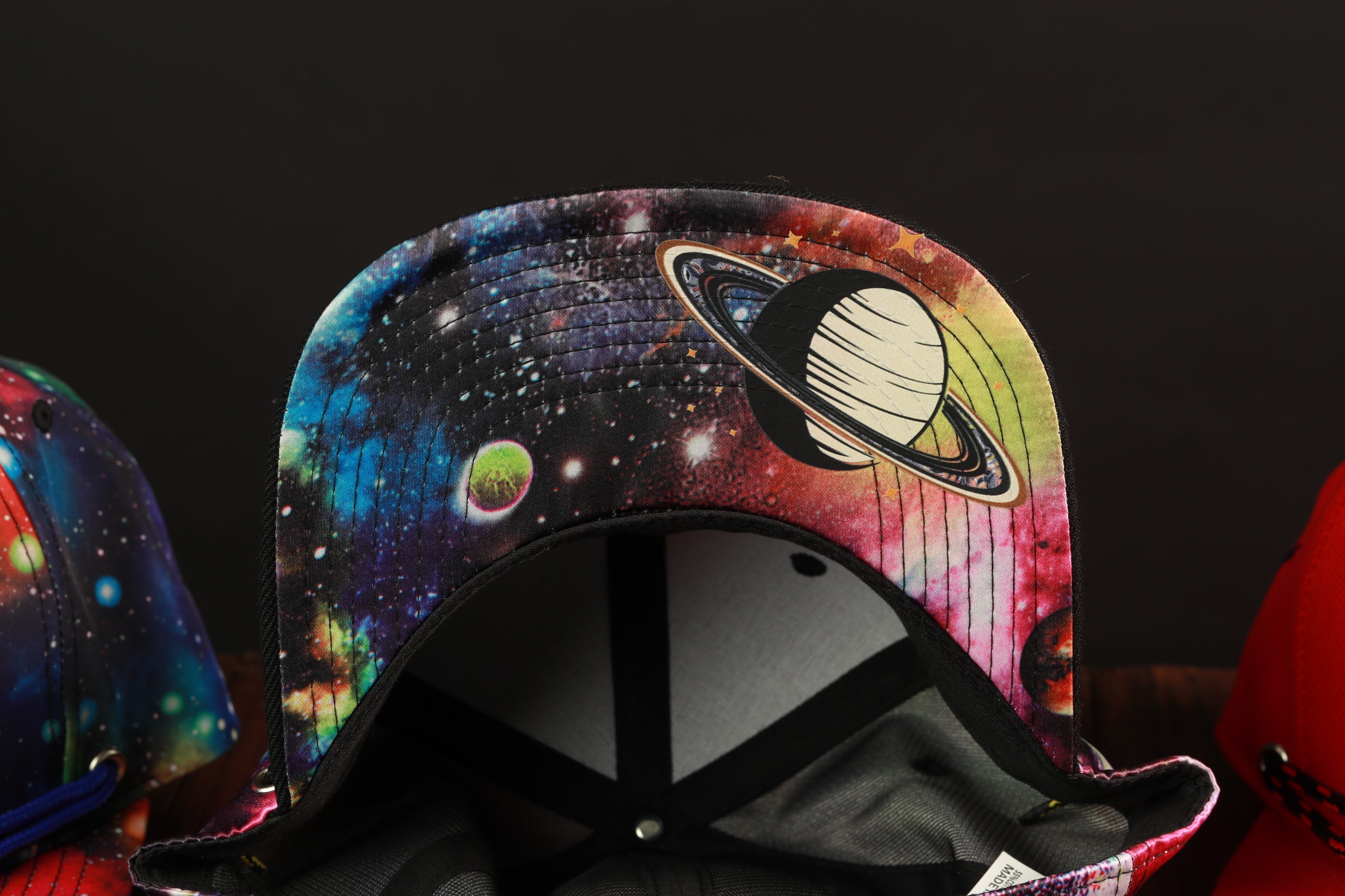 A colorful, space-themed baseball cap with a planet design on the front.