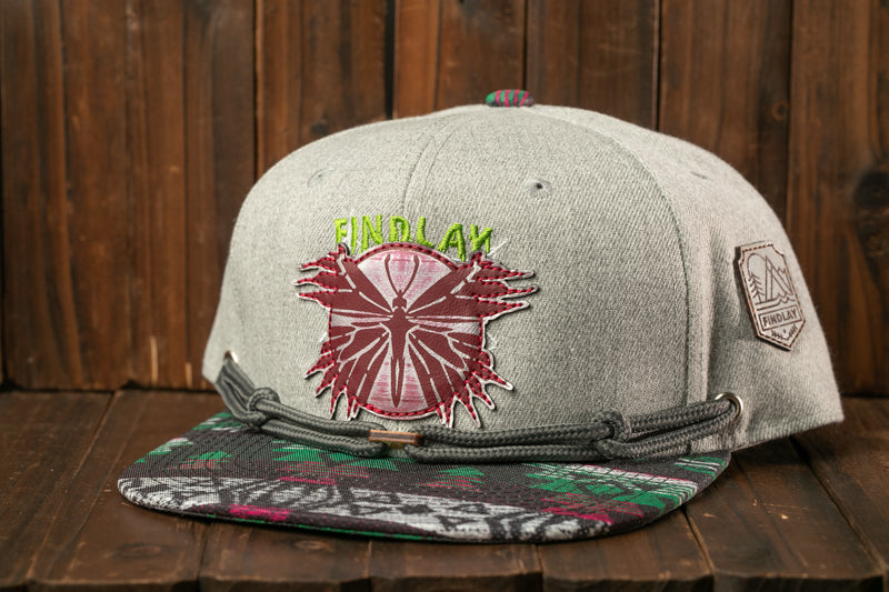 A gray baseball cap with a colorful, embroidered design on the front, placed on a wooden surface.