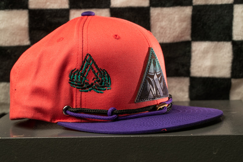A red baseball cap with a purple brim and a black and white checkered background.