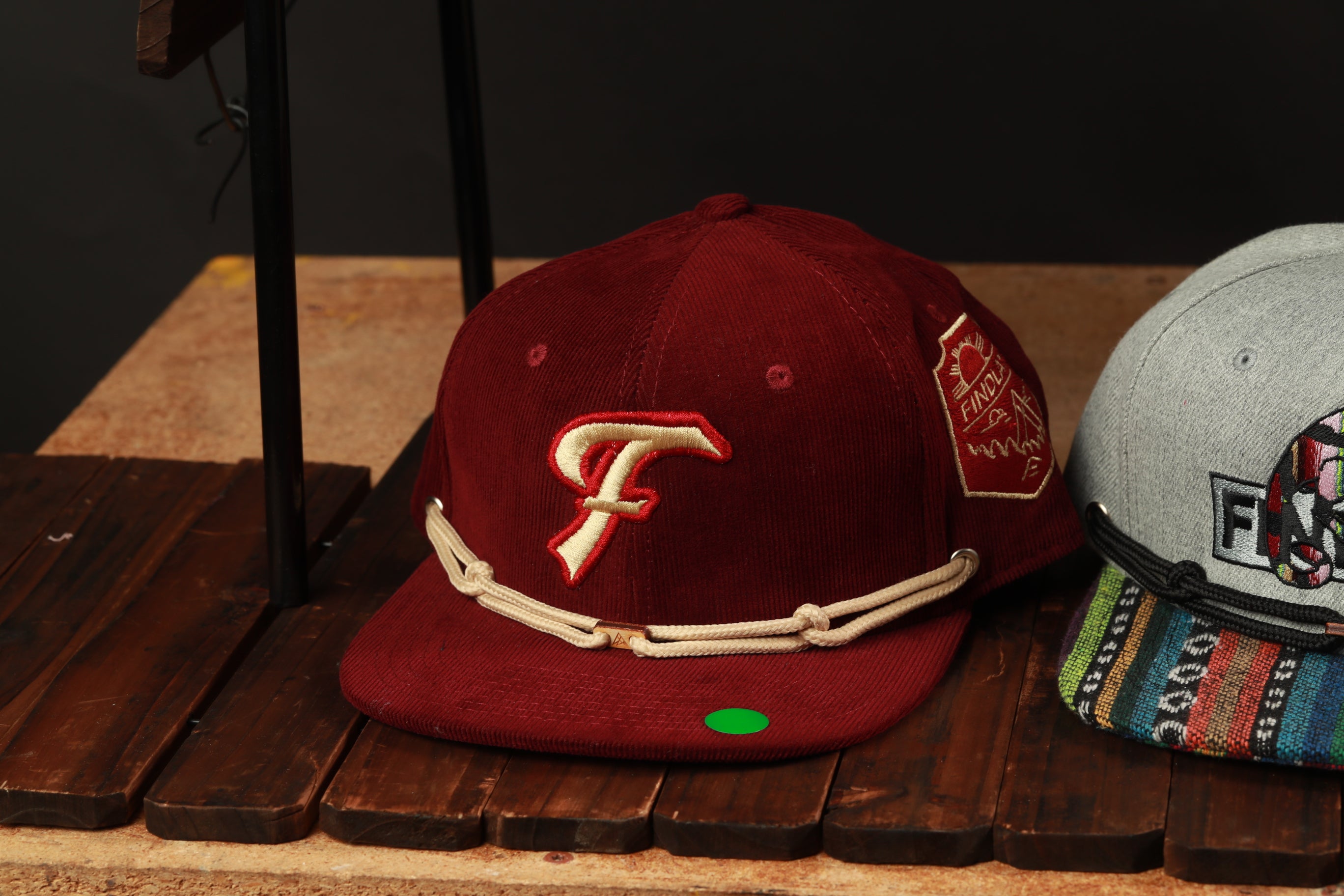two baseball caps on a wooden surface, one red and one gray.