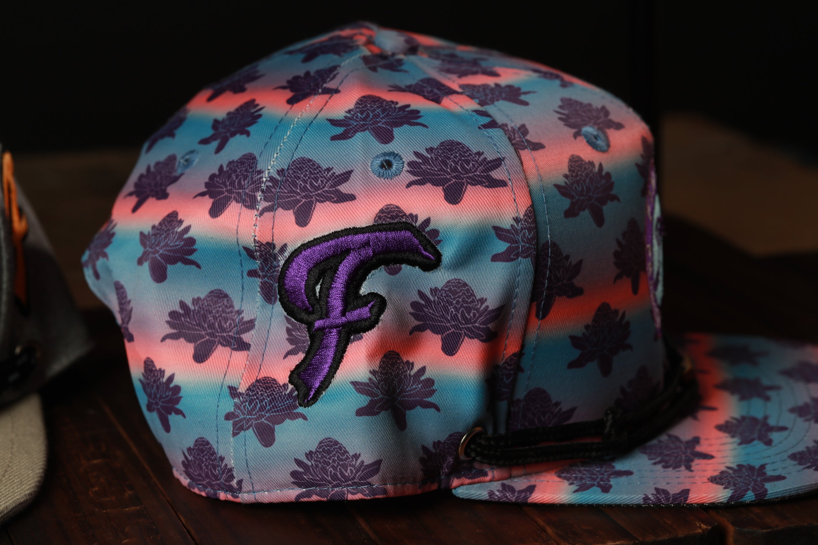 A colorful baseball cap with a floral pattern and a purple "F" logo on the front.