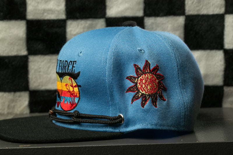 A blue baseball cap with a sun-shaped patch and a black brim, featuring a colorful design on the front.
