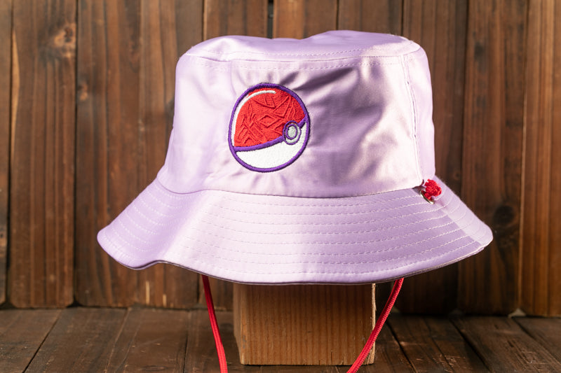 A purple bucket hat with a Pokemon-inspired design on the front, displayed on a wooden surface.