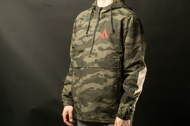 A person wearing a camouflage jacket with a red logo on the chest.