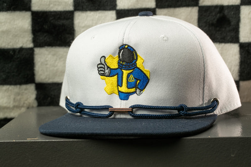 A white baseball cap with a yellow and blue embroidered character on it, wearing a blue helmet and giving a thumbs up.