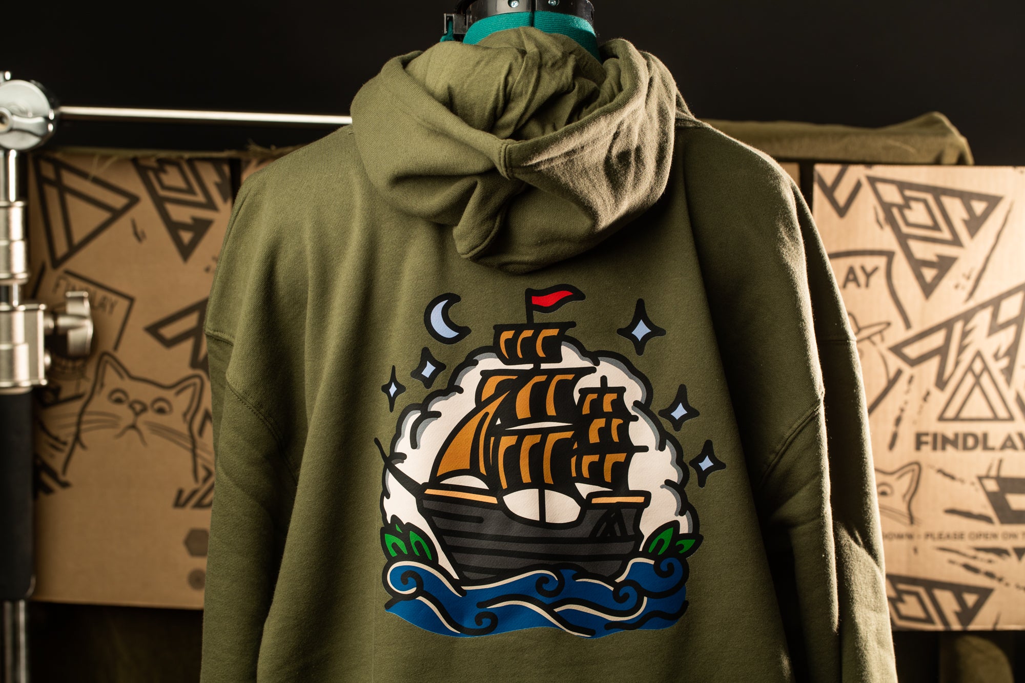 a green hoodie with a colorful graphic of a ship on the back.