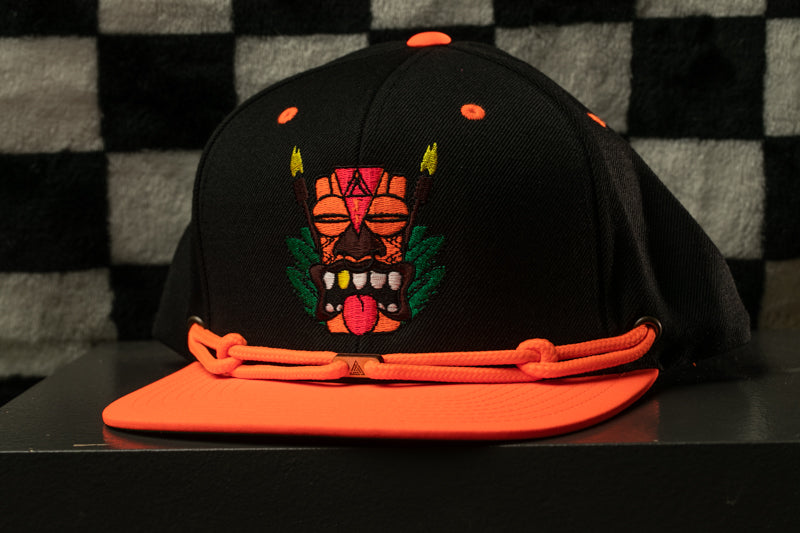 A black baseball cap with an orange brim and a colorful tiki mask design on the front.