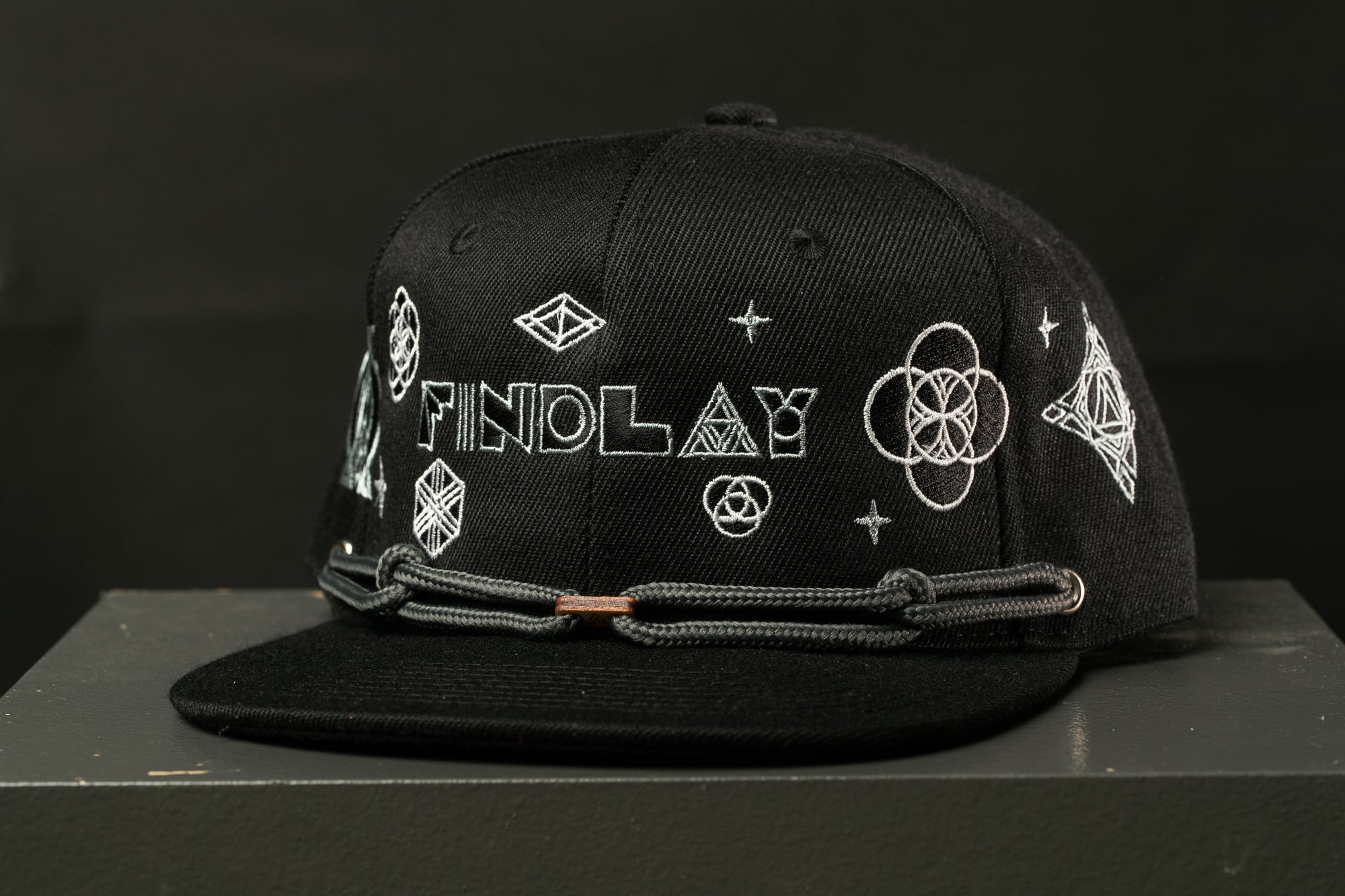A black baseball cap with white text and geometric designs on it.