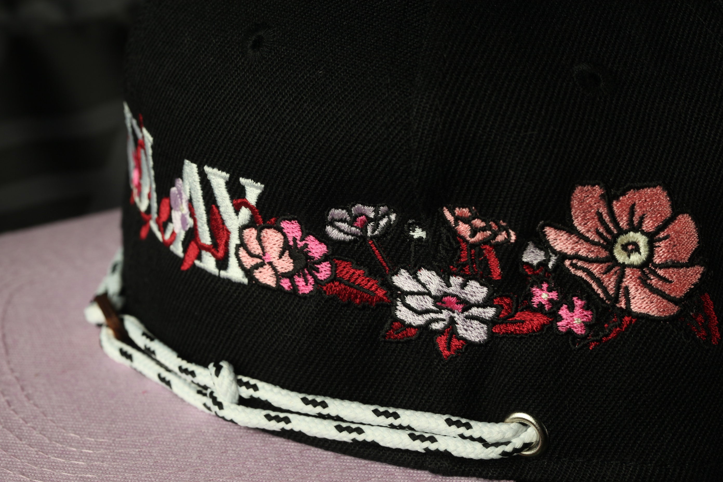 A close-up view of a black baseball cap with colorful floral embroidery.