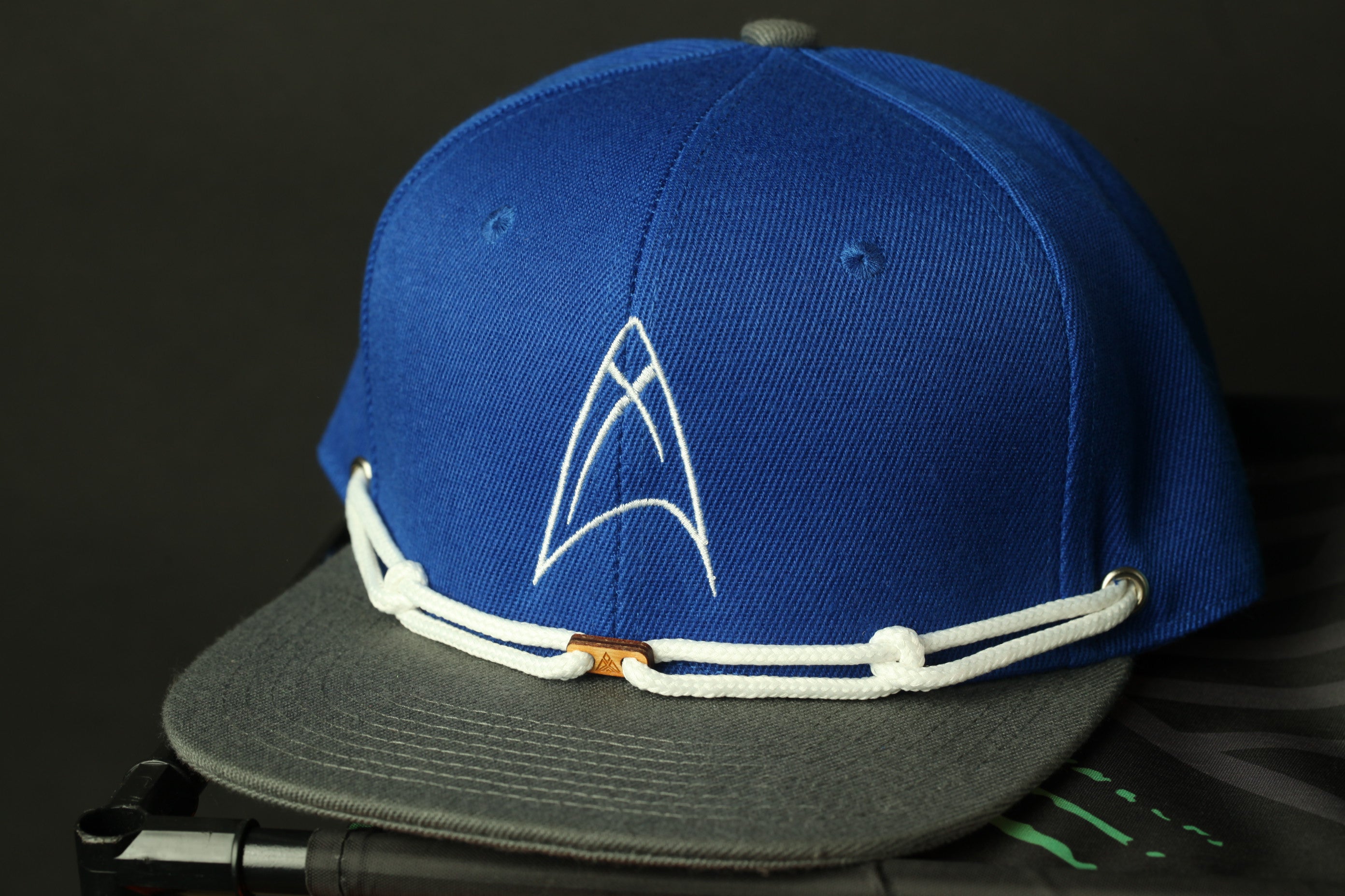 A blue baseball cap with a white star logo, resting on a gray surface.