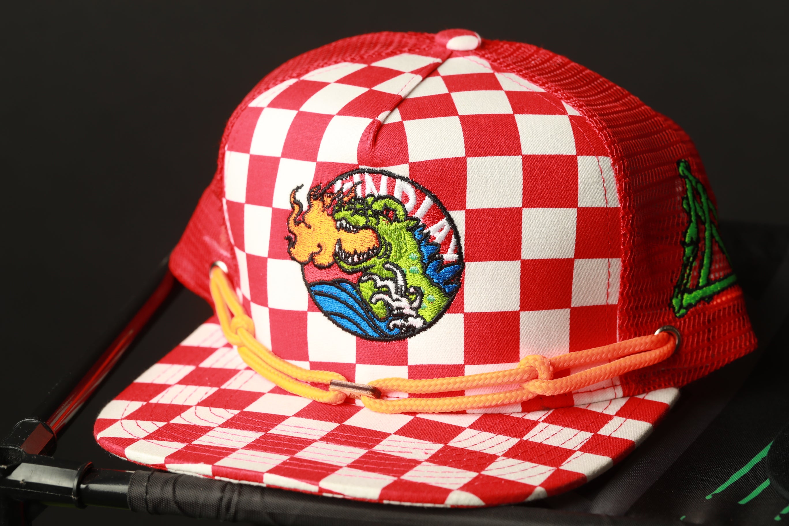 A red and white checkered baseball cap with a colorful dragon design on the front.