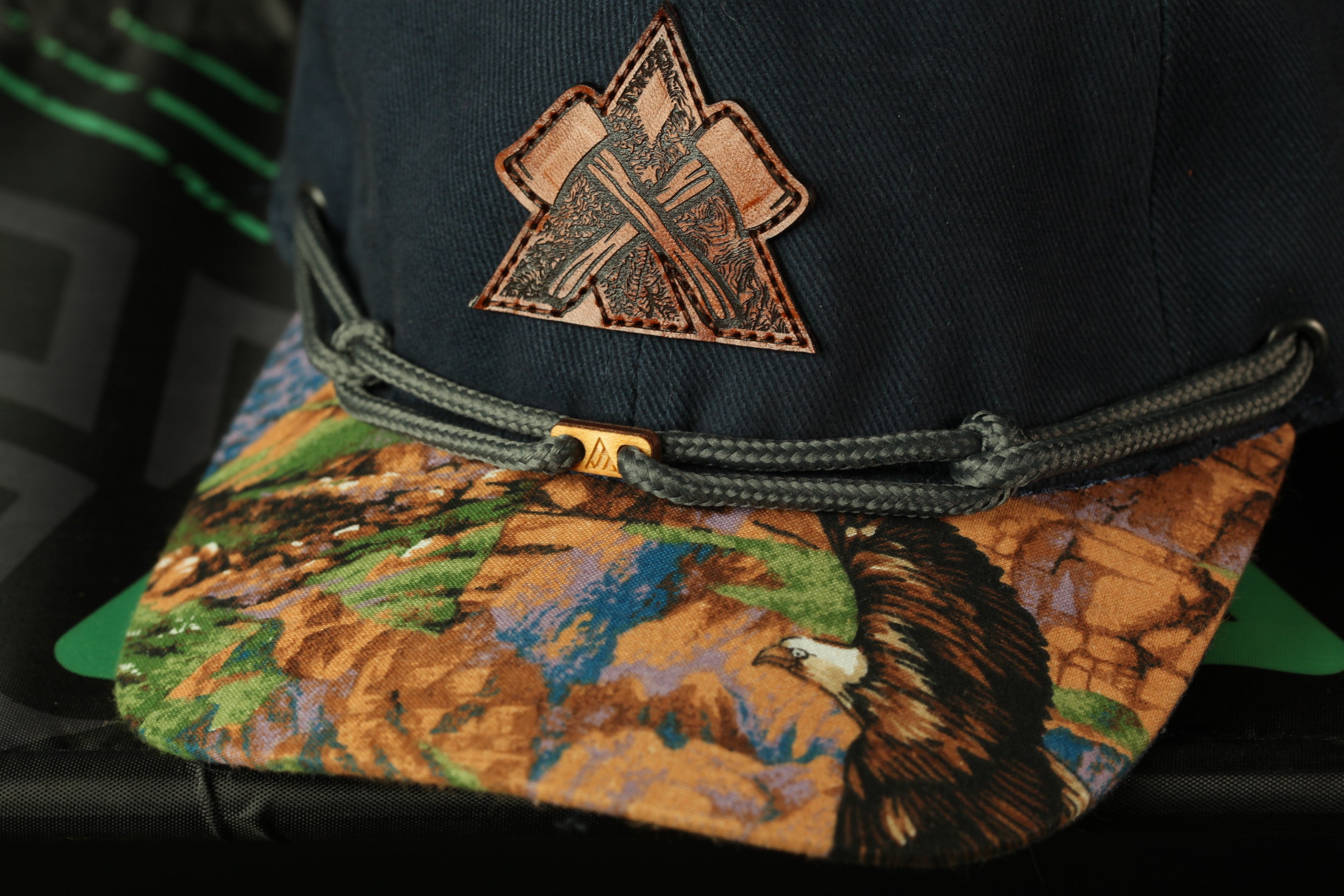 A close-up view of a baseball cap with a distinctive embroidered logo on the front.