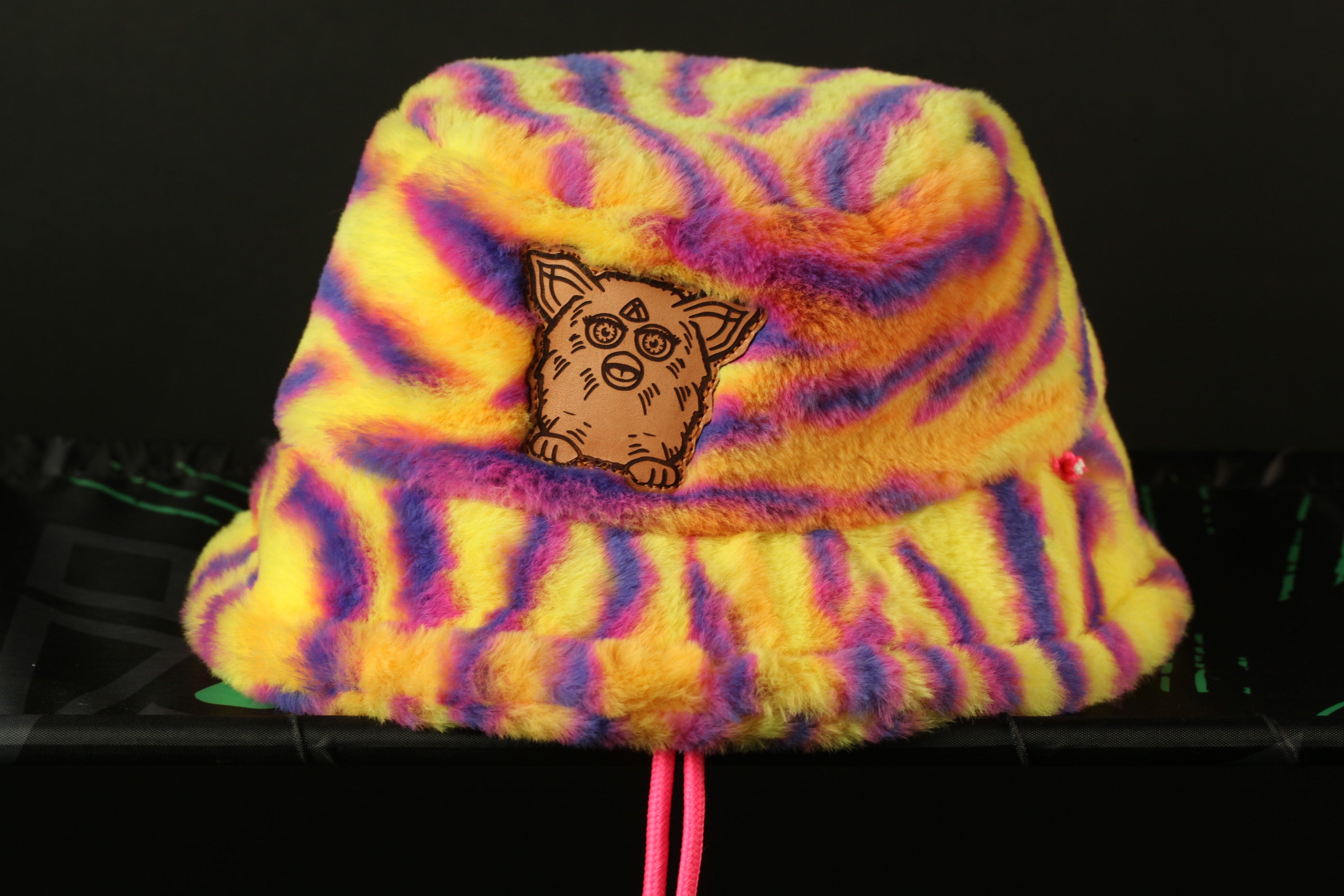 A colorful, tie-dye bucket hat with a cartoon character design on the front.