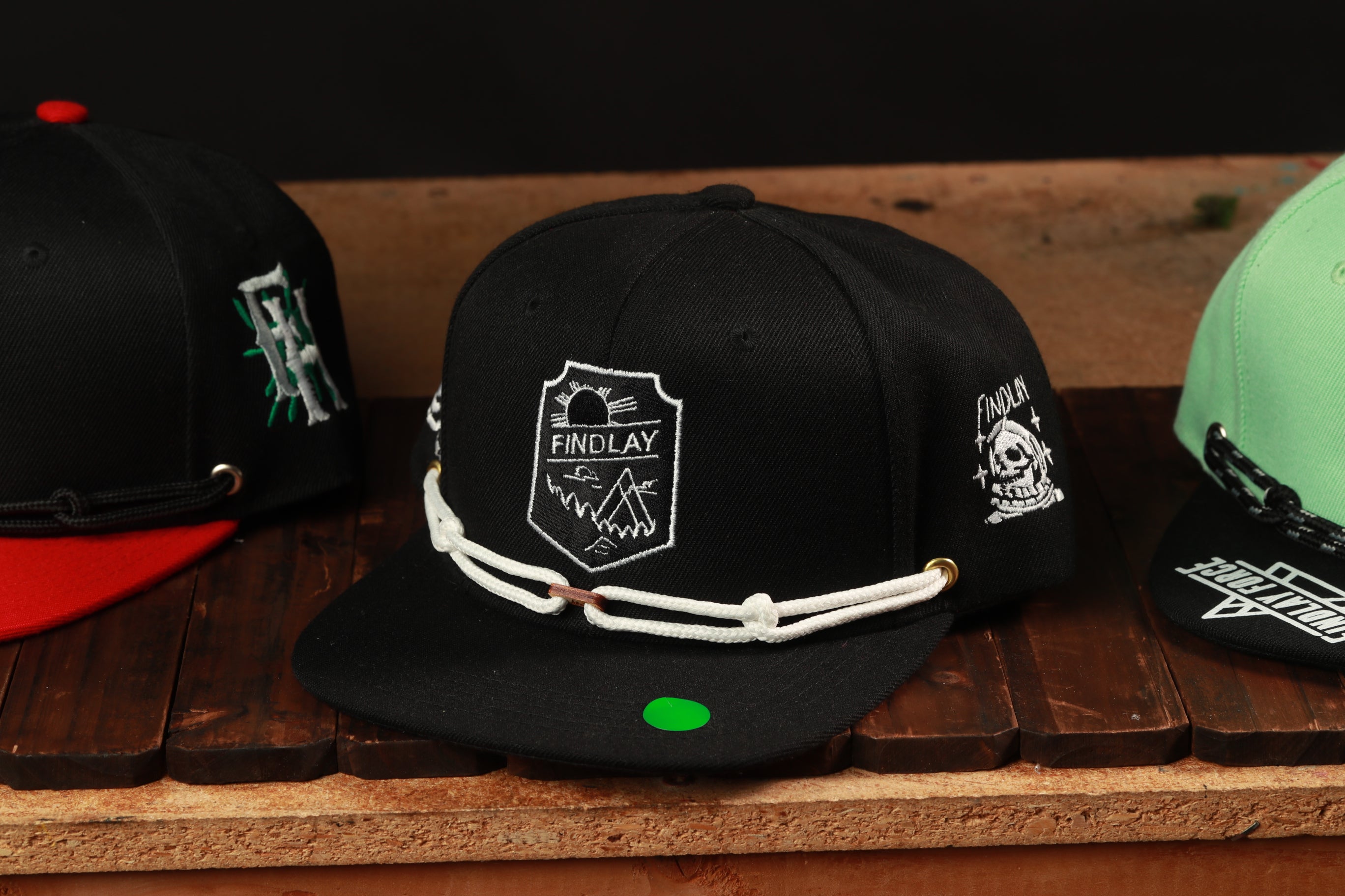 A collection of three baseball caps, each with unique designs and colors, displayed on a wooden surface.