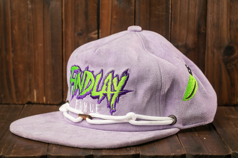 A purple baseball cap with the text "Findlay" printed on it, sitting on a wooden surface.