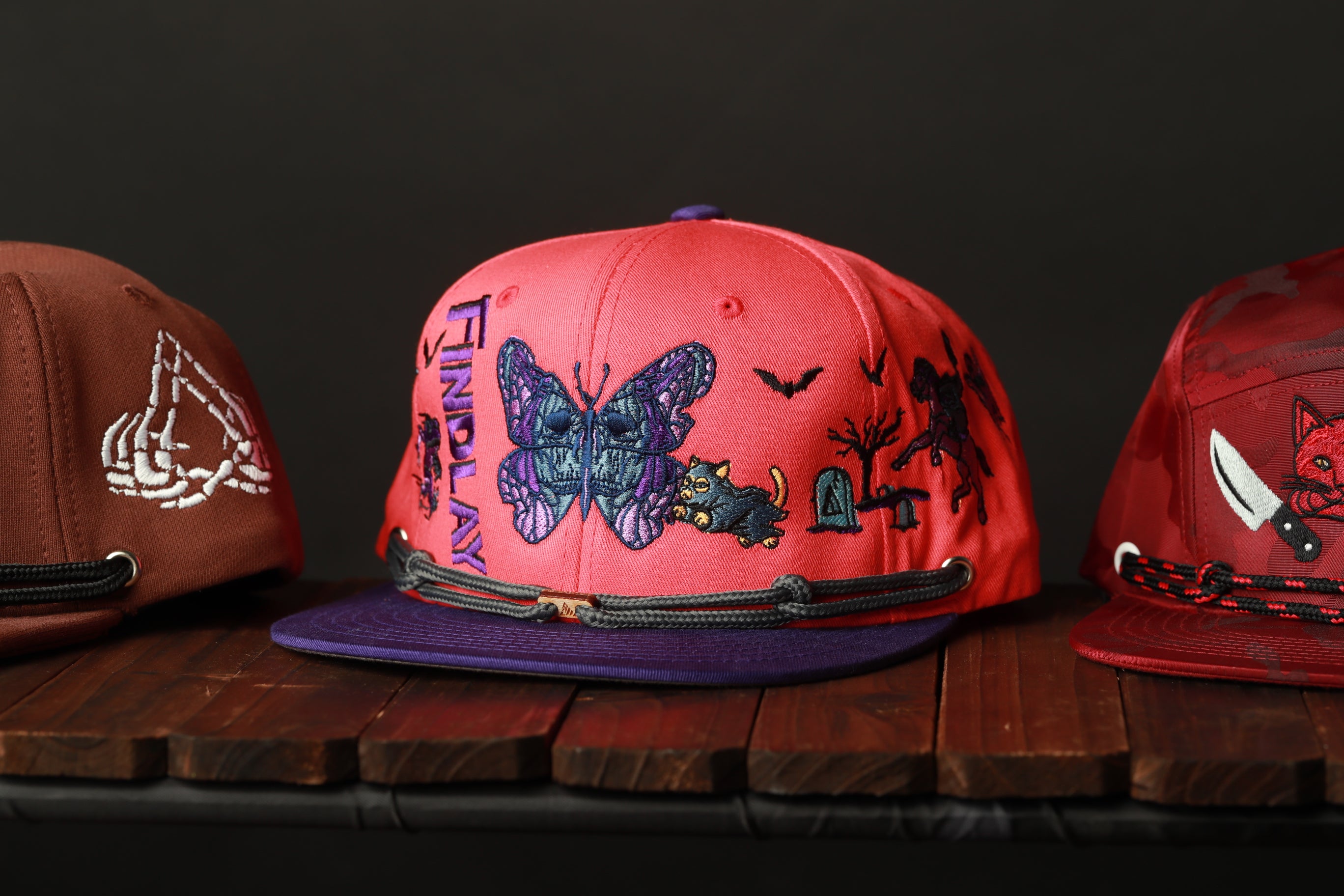 Three colorful baseball caps are displayed on a wooden surface.