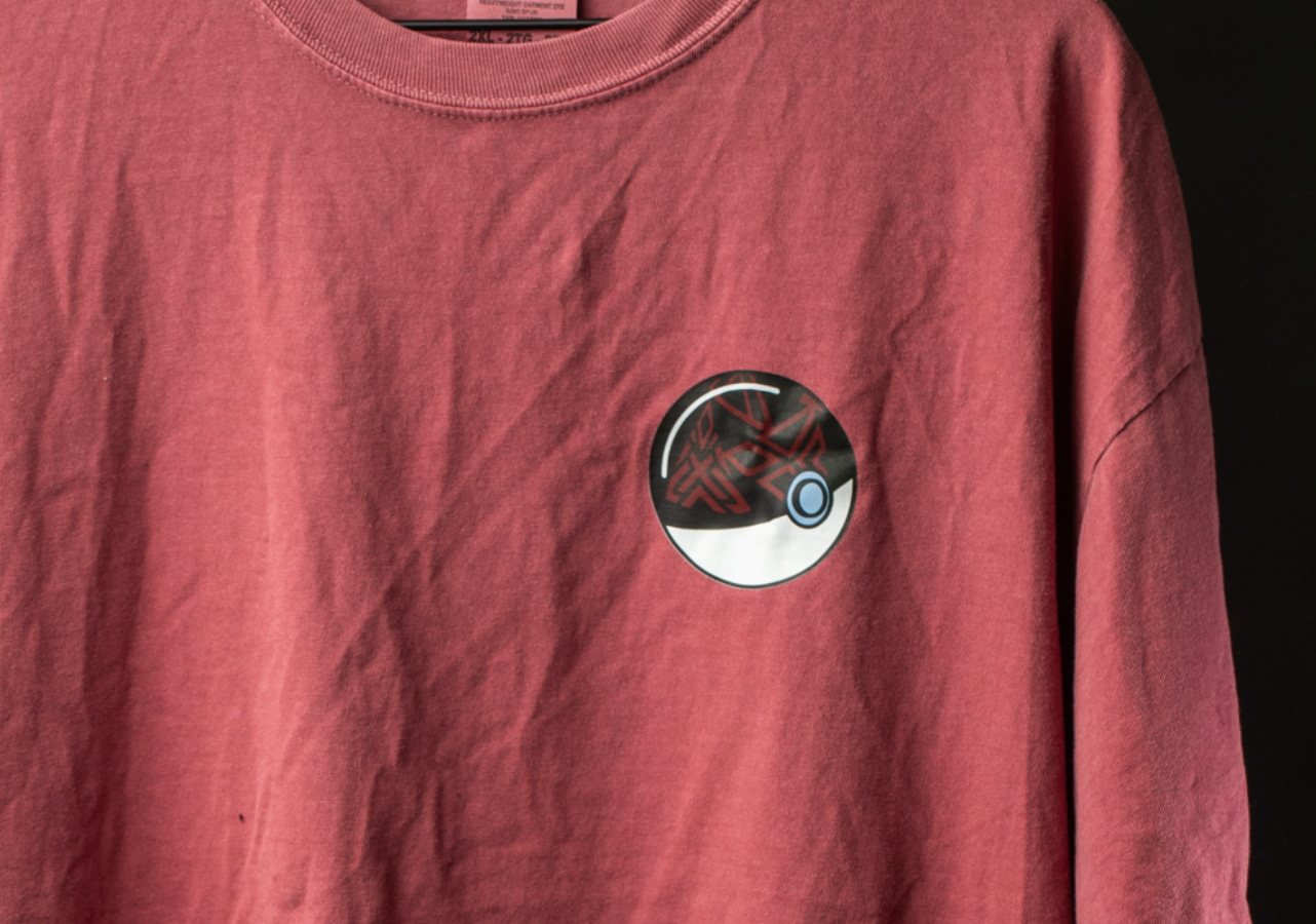 A close-up view of a red t-shirt with a circular design on the front, featuring a black and white pattern.