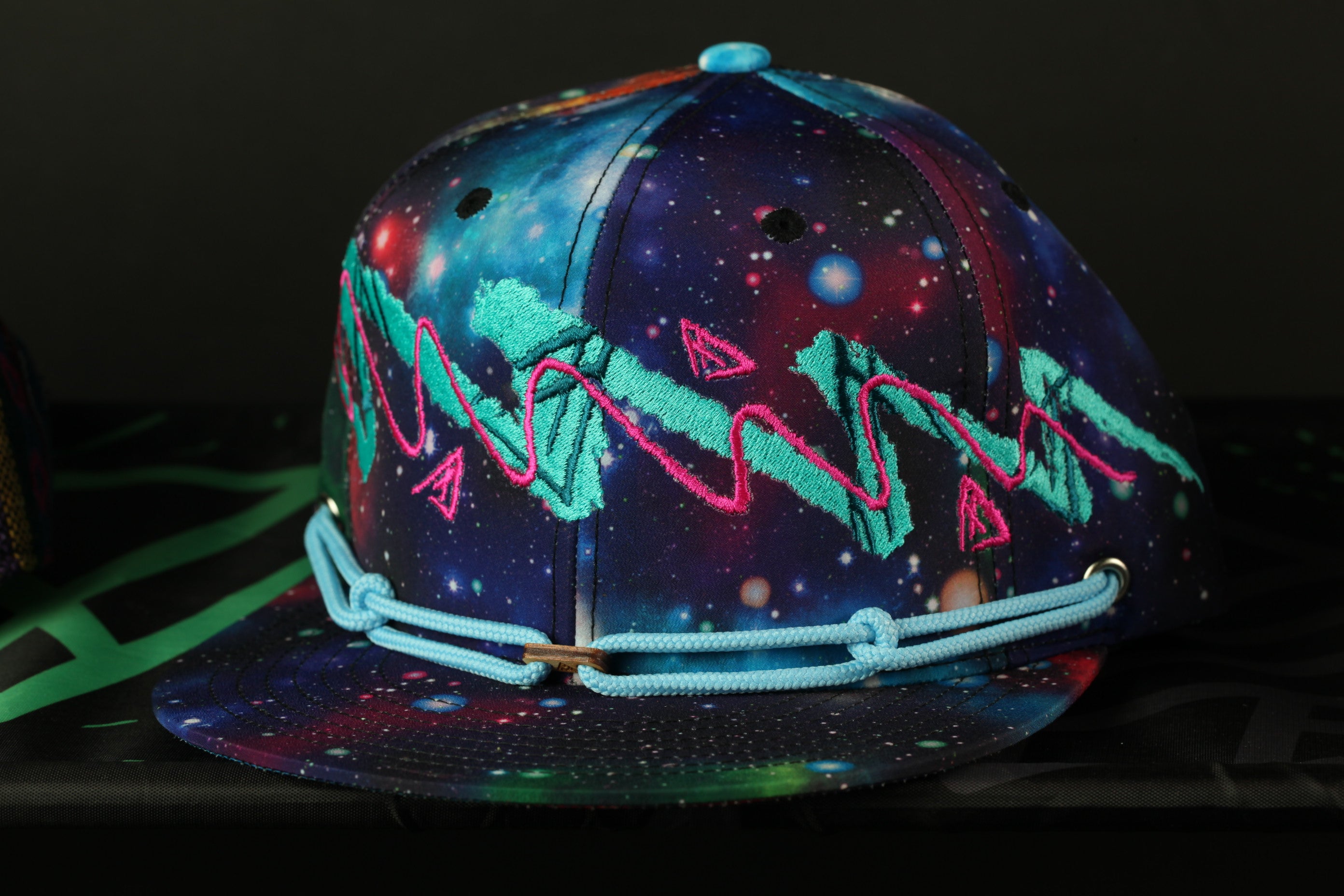 A colorful, patterned baseball cap with a galaxy-themed design, featuring vibrant colors and abstract shapes.