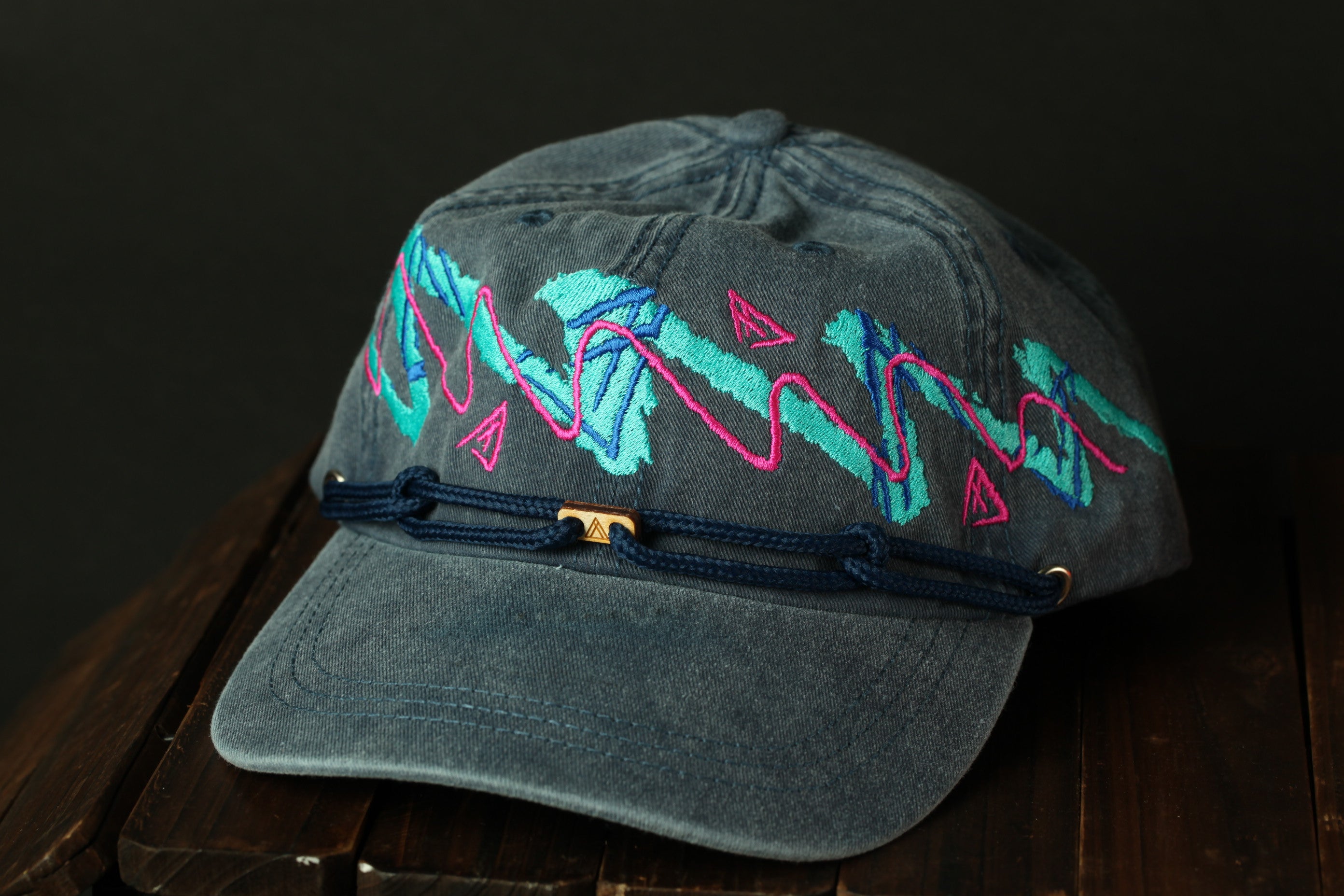 A gray baseball cap with colorful geometric designs and a metal clasp on the front.