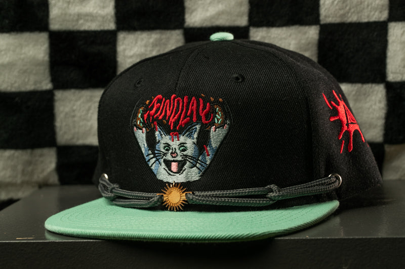 A black baseball cap with a cat design and a sun-shaped charm on the brim.