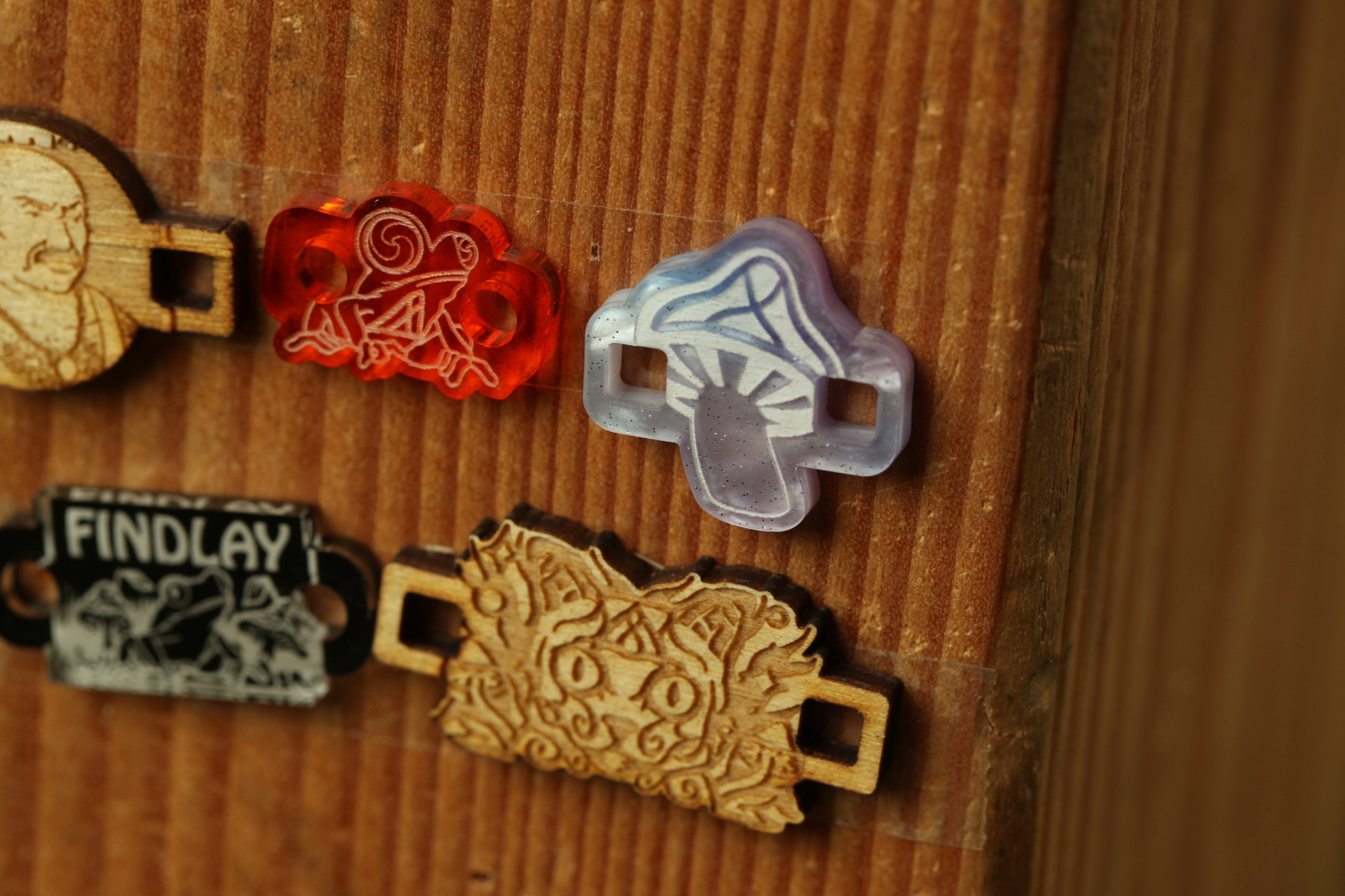 a wooden surface with various colorful and intricate wooden objects, including a mushroom-shaped object, a red and white object, and a wooden tag with a black and white design.
