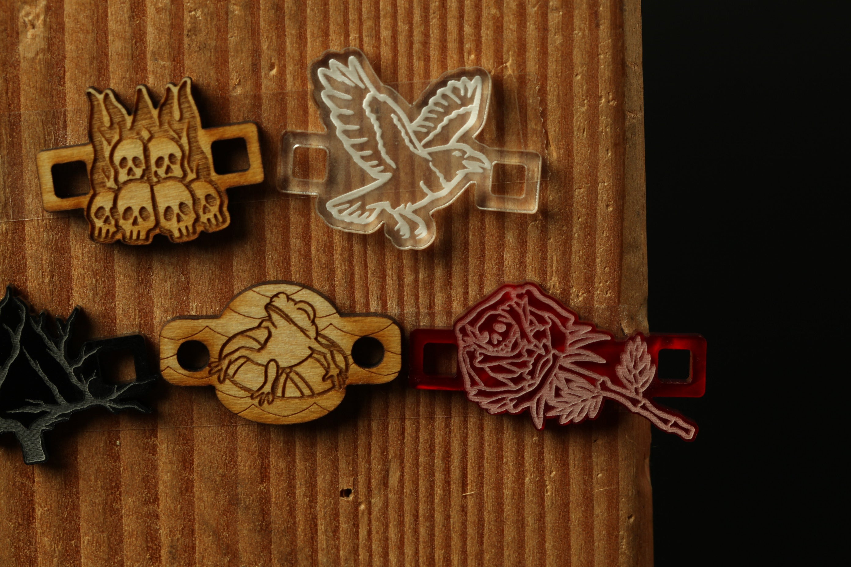 a collection of various wooden and plastic objects, including a wooden skull, a wooden frog, a wooden rose, and a wooden leaf, all displayed on a wooden surface.