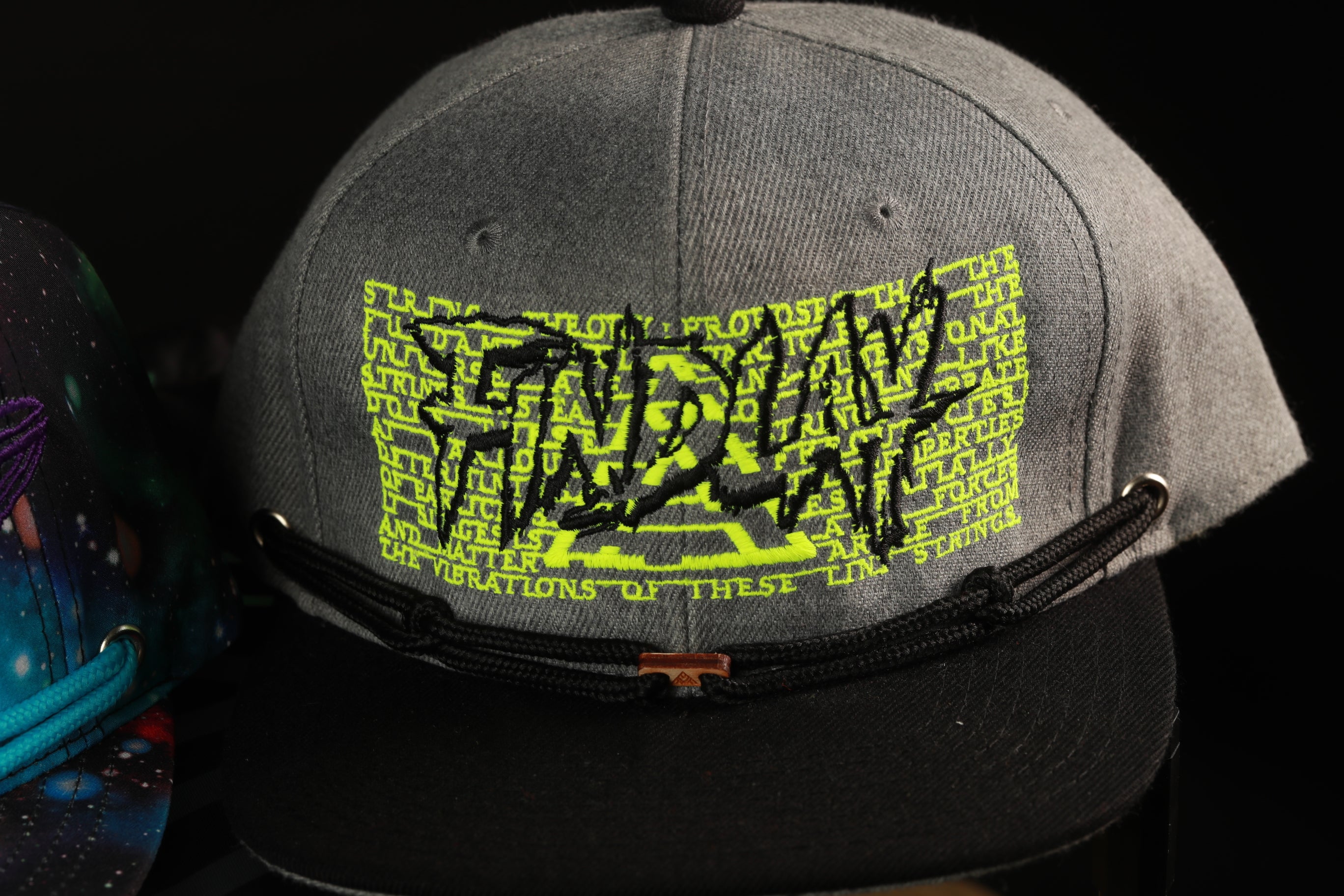 A gray baseball cap with a black strap and a yellow graphic design on the front.