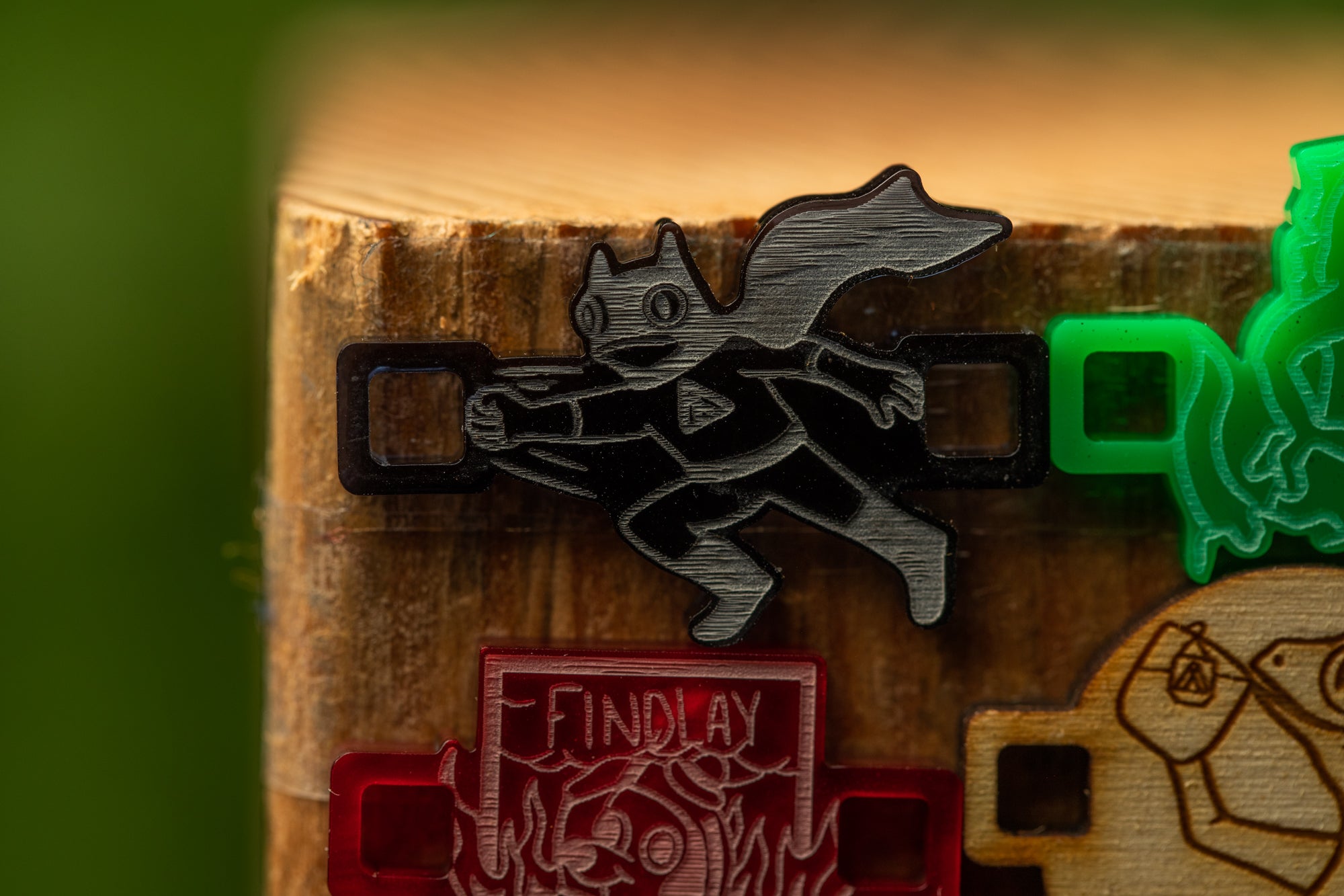 a close-up view of a wooden surface with a black and silver metal object, which appears to be a decorative piece or a small sculpture. The object has a stylized, cartoonish design, resembling a cat or a bird. The wooden surface is made of wood, and there are other objects in the background, but they are not the main focus of the image.