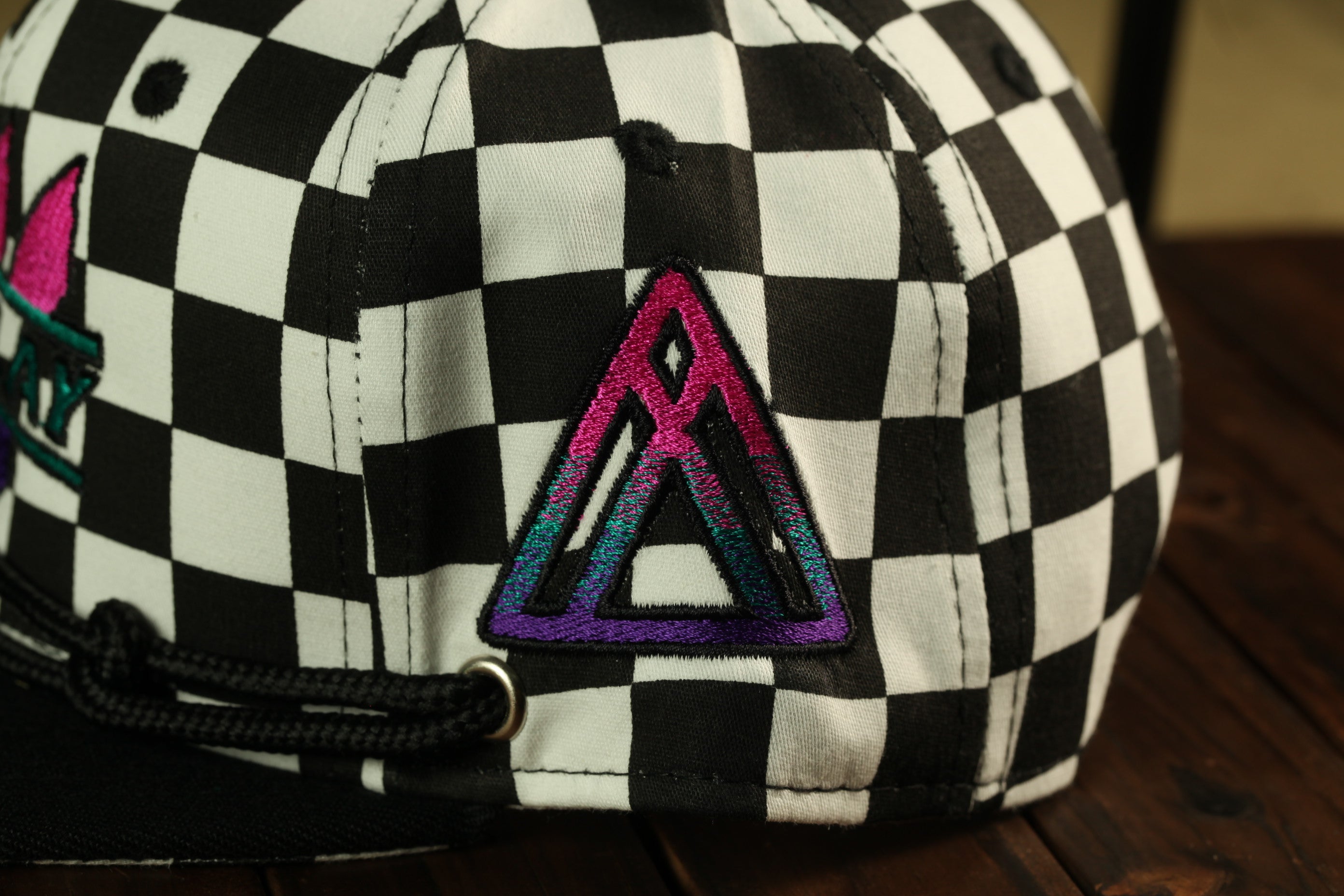 a close-up view of a black and white checkered baseball cap with a colorful triangle patch on the front.