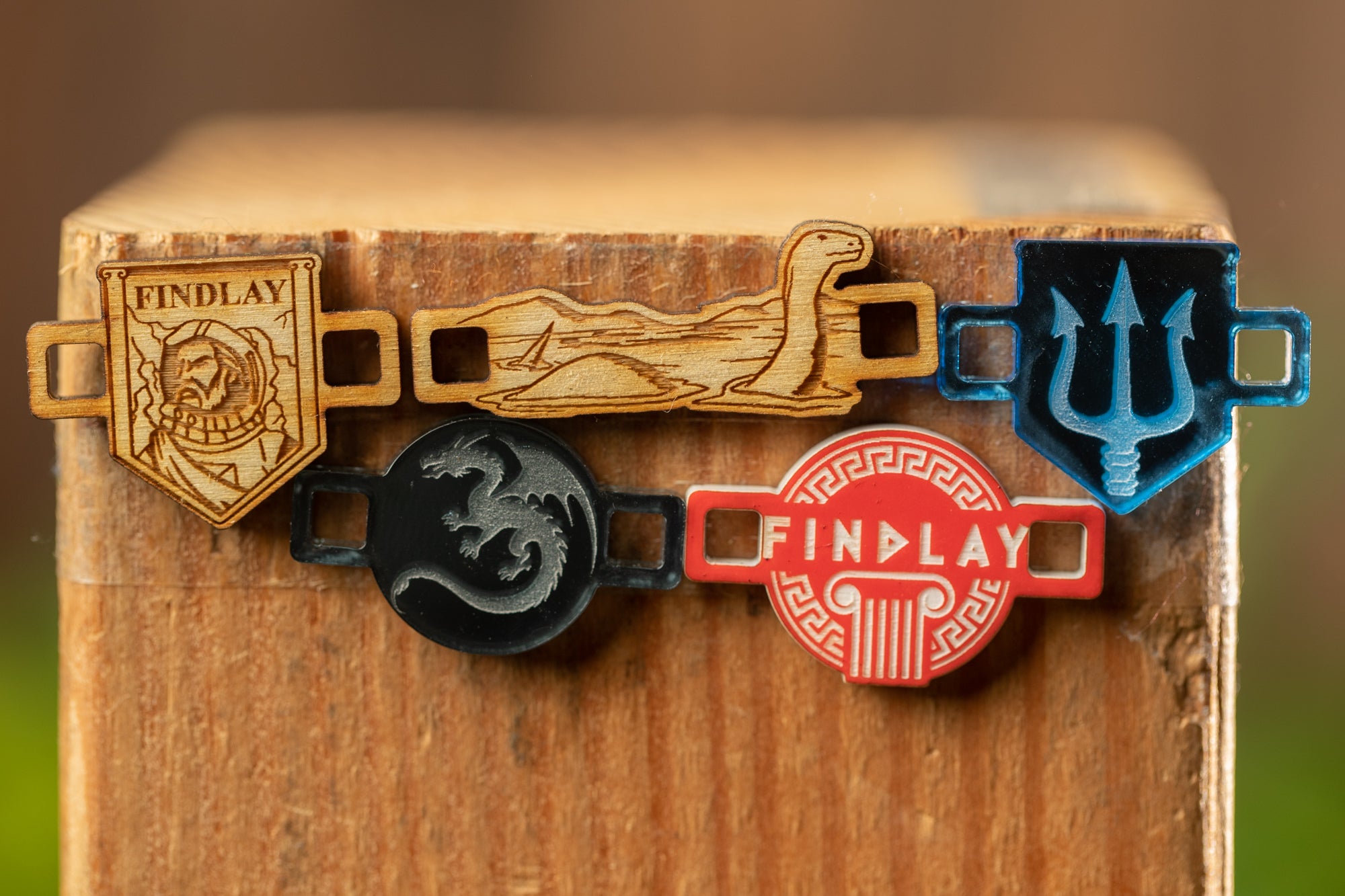 a wooden surface with four distinct pieces of jewelry or accessories attached to it.