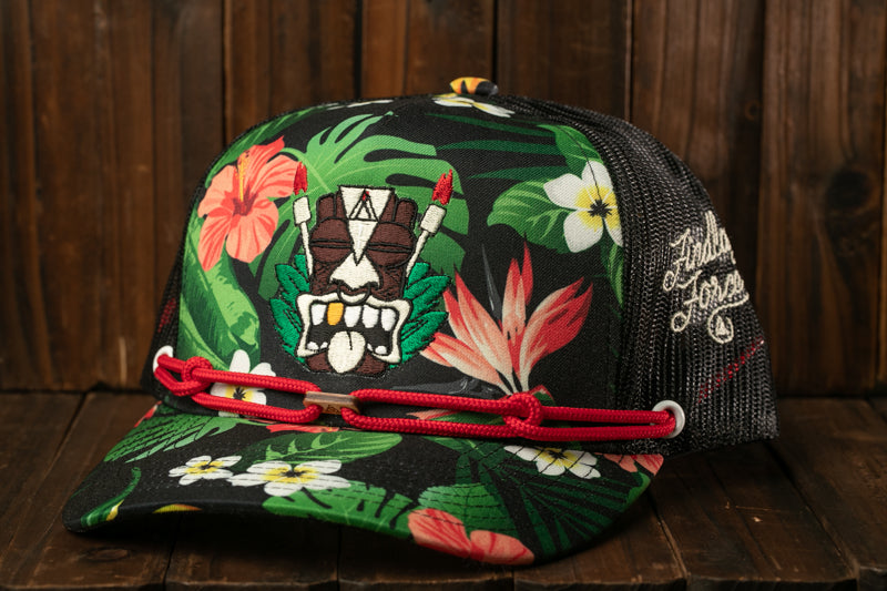 A colorful baseball cap with a tropical print design, featuring a tiki mask and various flowers and leaves.