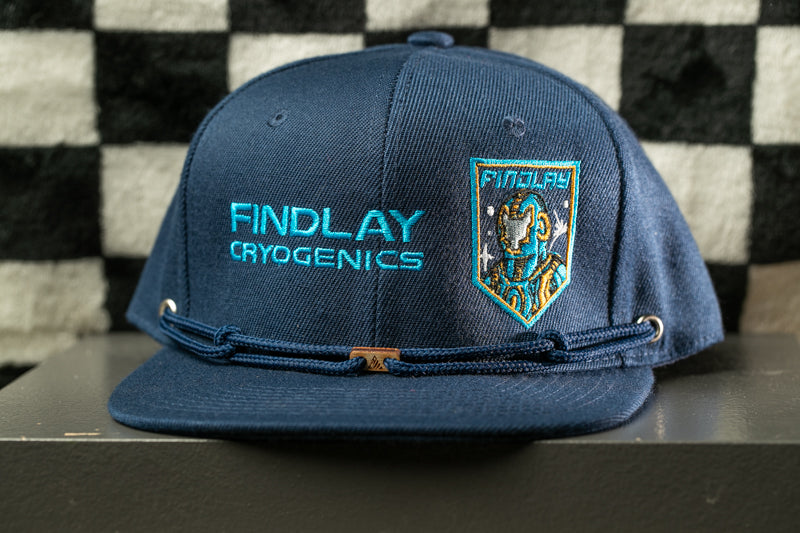 A navy blue baseball cap with the text "FINDLAY CRYOGENICS" printed on it, along with a small patch on the front featuring a space-themed design.